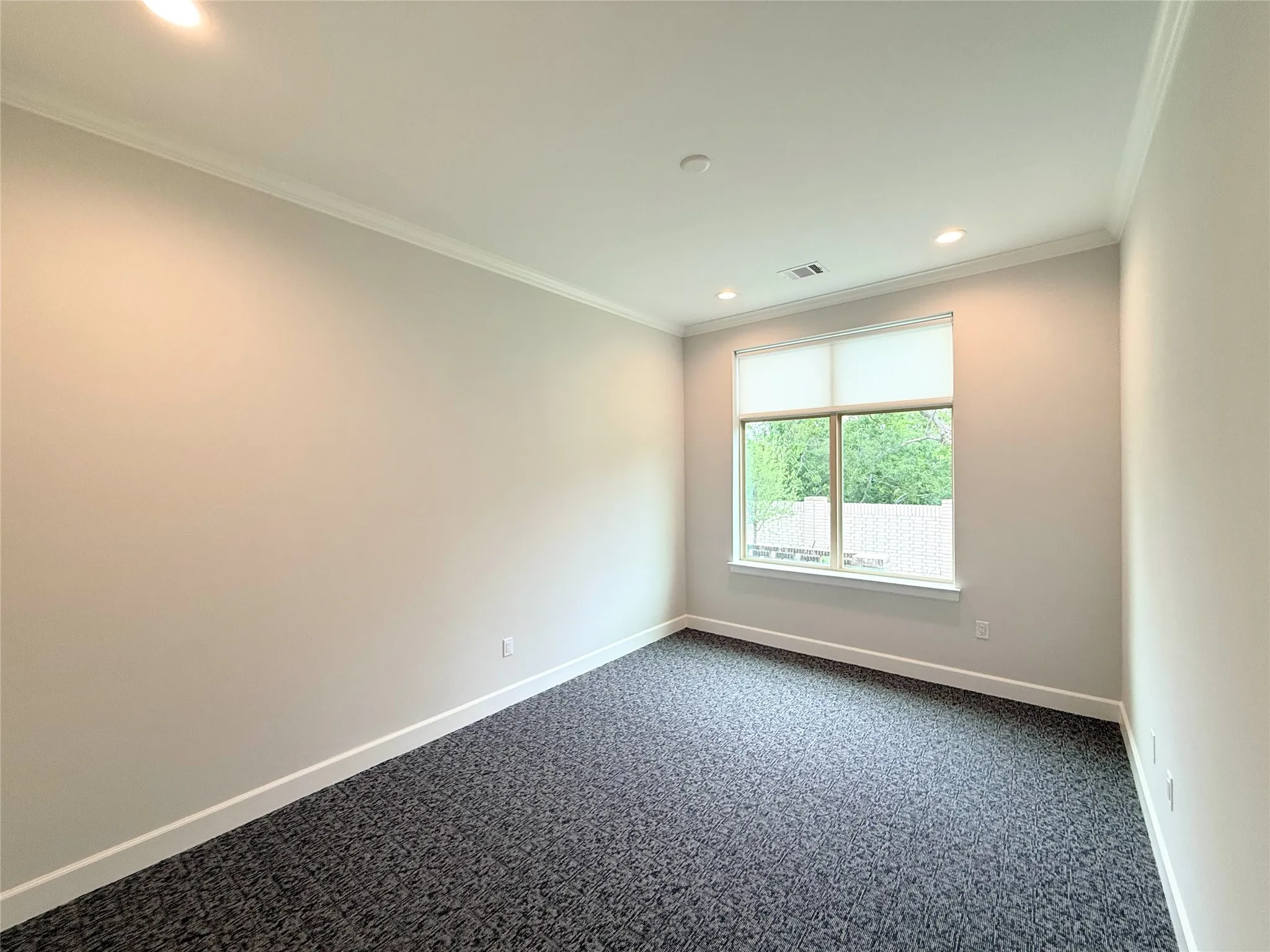 Spacious room featuring a large window, recessed lighting, crown molding, light-toned walls, and patterned carpet flooring