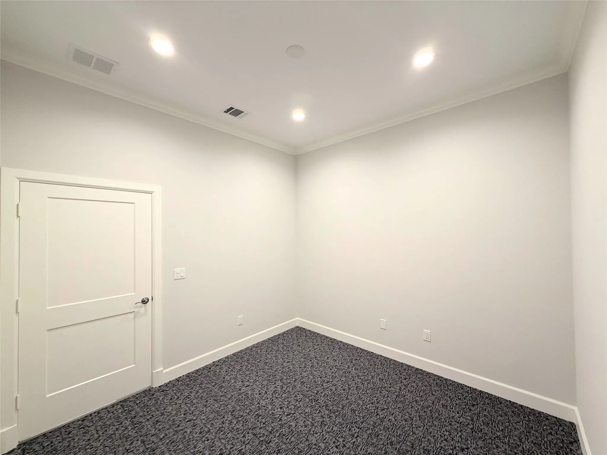 White interior door, crown molding, recessed lighting, baseboards, and textured carpet