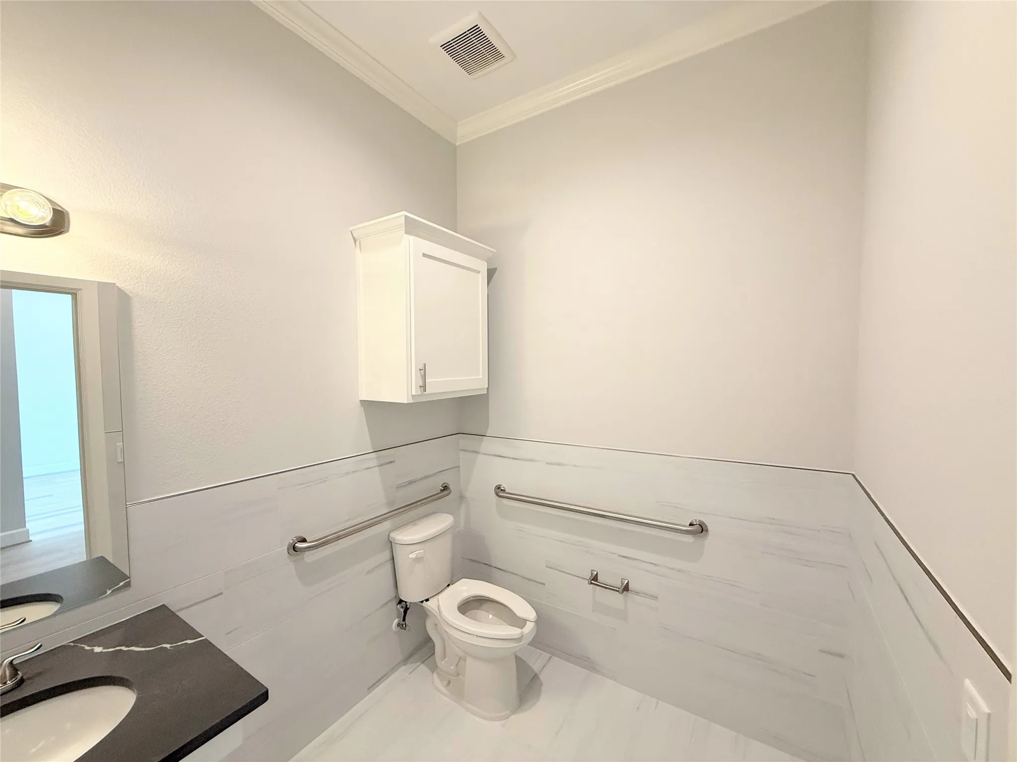 Bathroom featuring white wall tile, a white toilet, and a vanity with a dark countertop and undermount sink