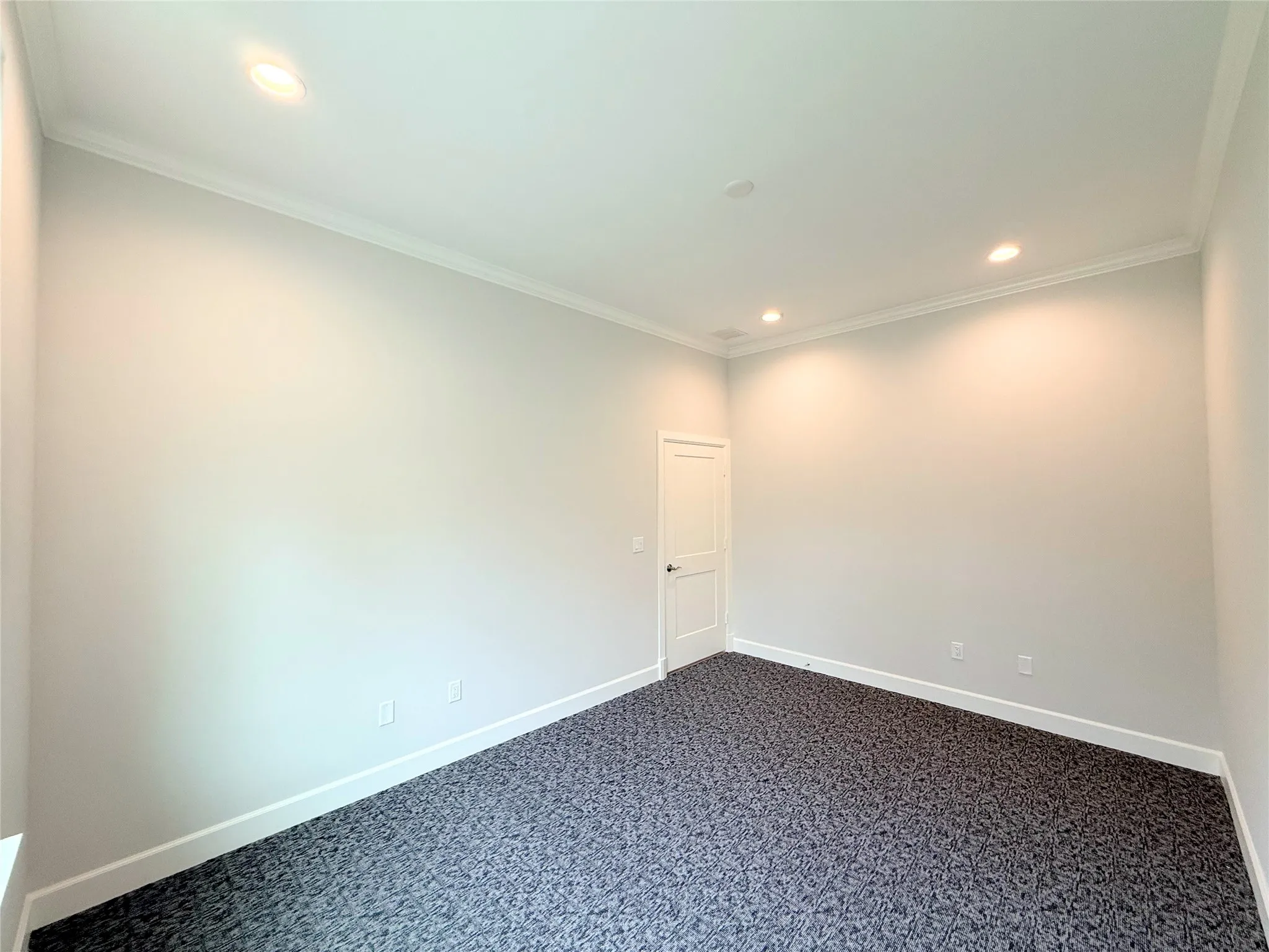 Spacious room featuring patterned carpet flooring, recessed lighting, crown molding, and crisp white baseboards