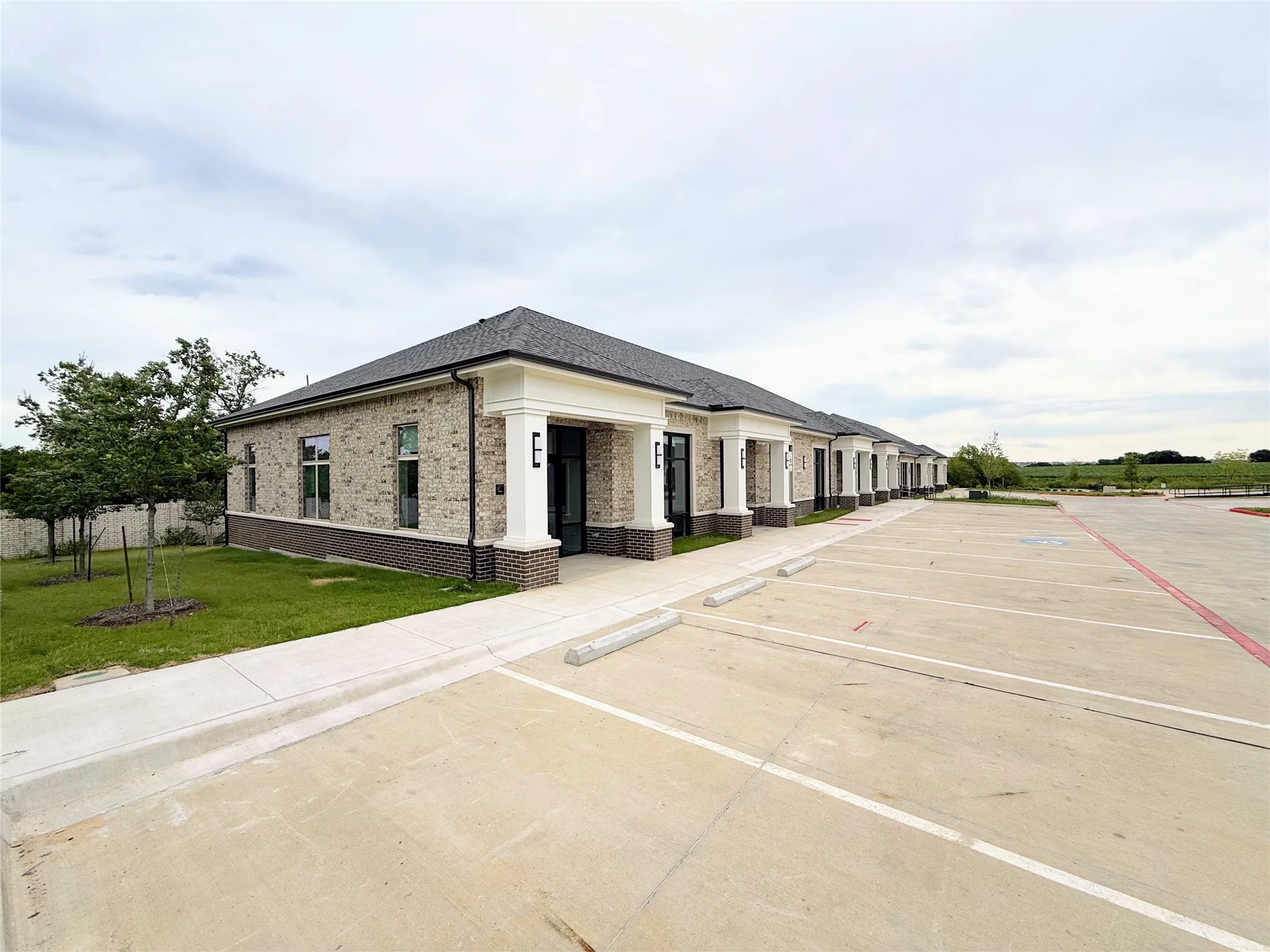Brick exterior featuring multiple entryways with white columns and dark trim