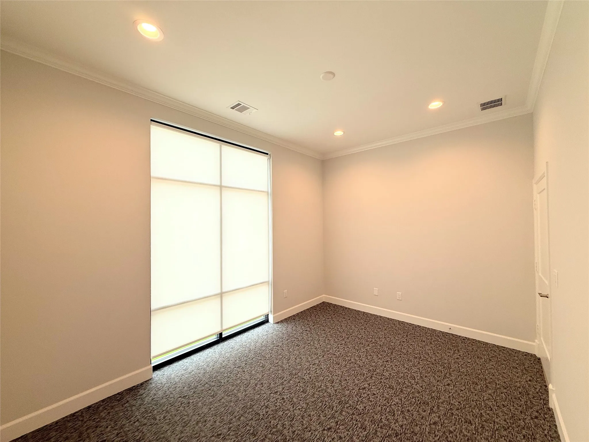 Floor-to-ceiling window with privacy shades, recessed lighting, crown molding, and neutral-toned carpeting