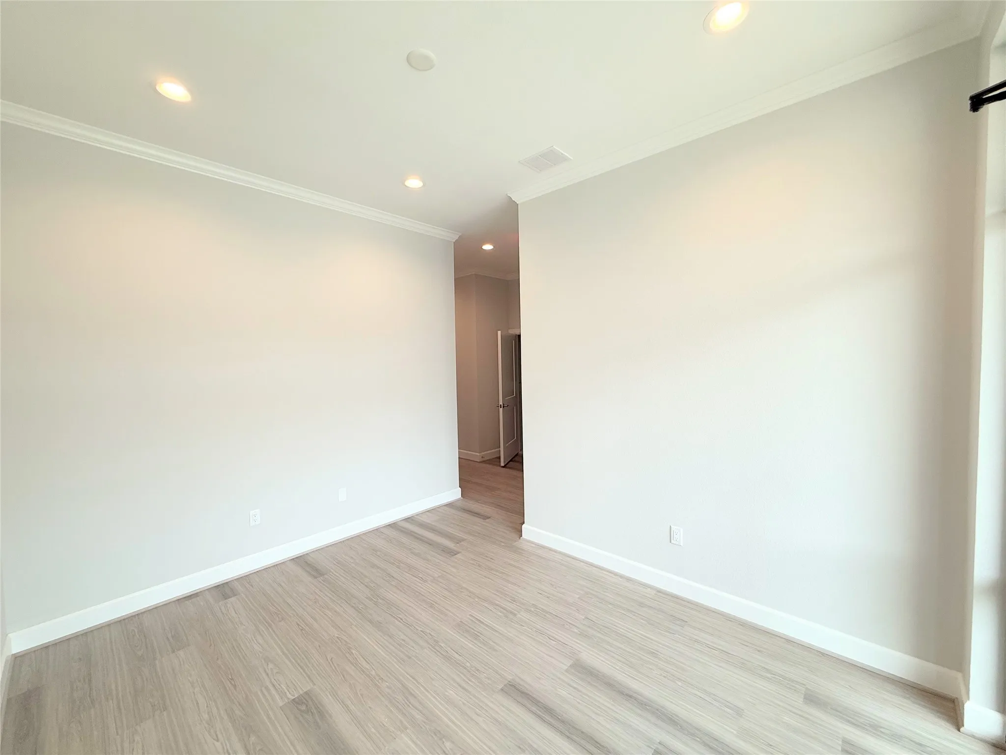 Bright interior space featuring light wood-finish flooring, recessed lighting, and crown molding