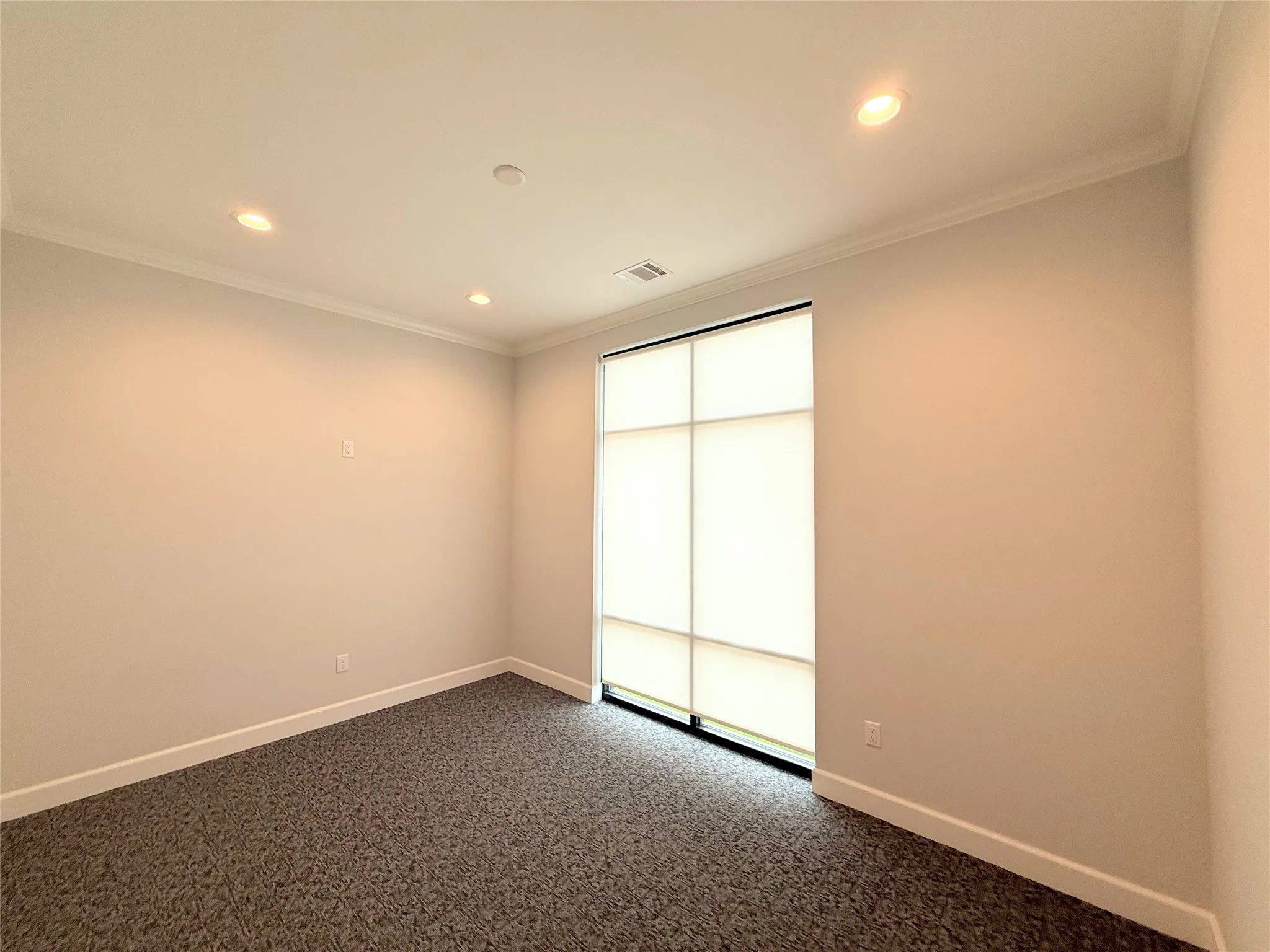 Room featuring a large window with frosted panels and privacy shades, recessed lighting, crown molding, and textured carpet flooring