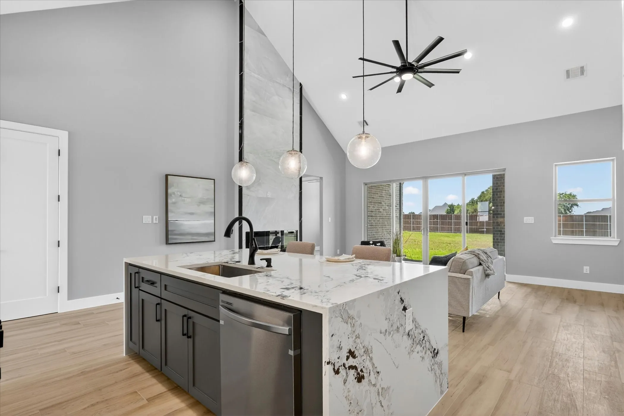 Kitchen island with waterfall countertop, black cabinetry, and undermount sink