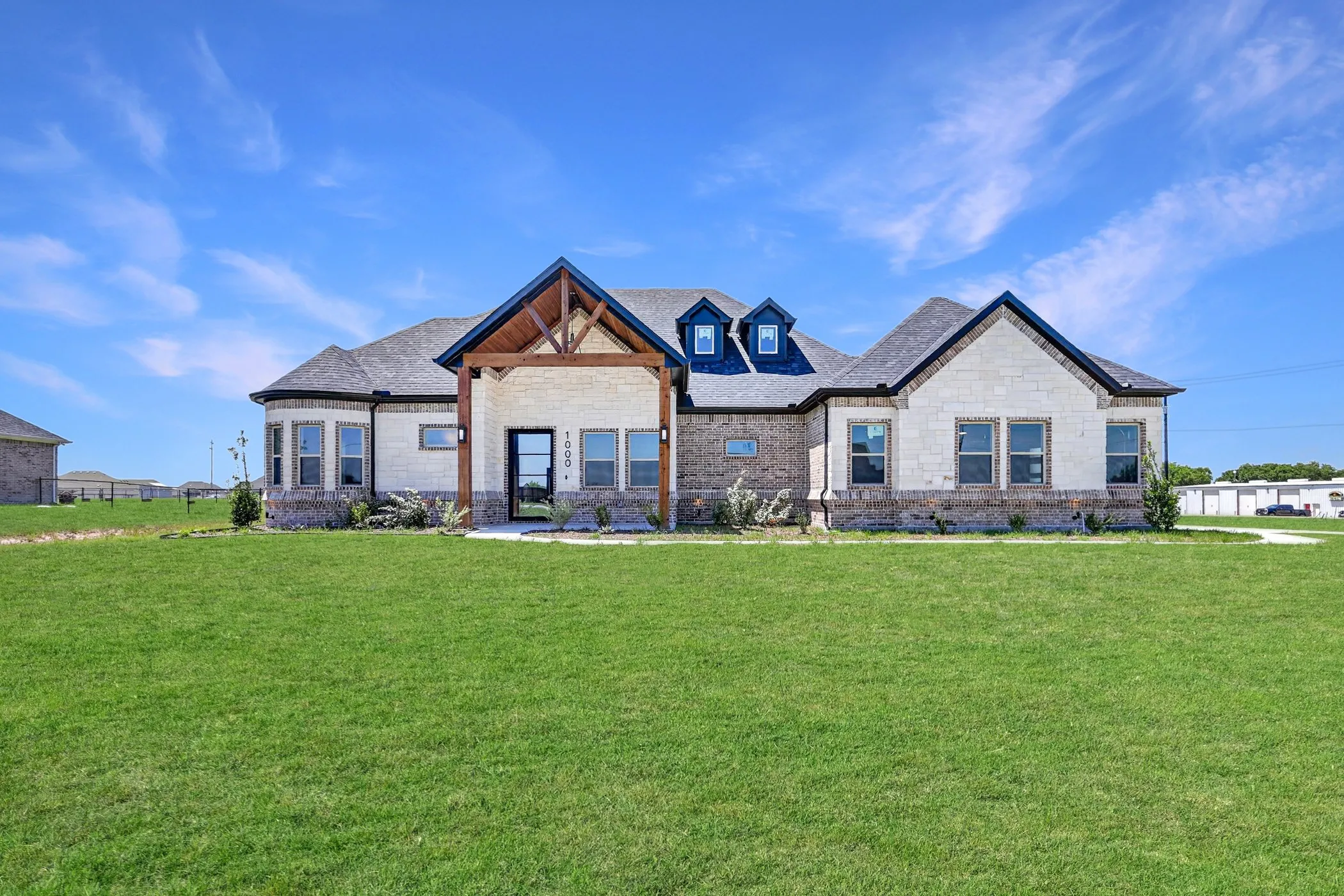 Single-story home featuring a combination brick and stone facade, a prominent gabled entry with exposed wood detailing, and multiple dormer windows
