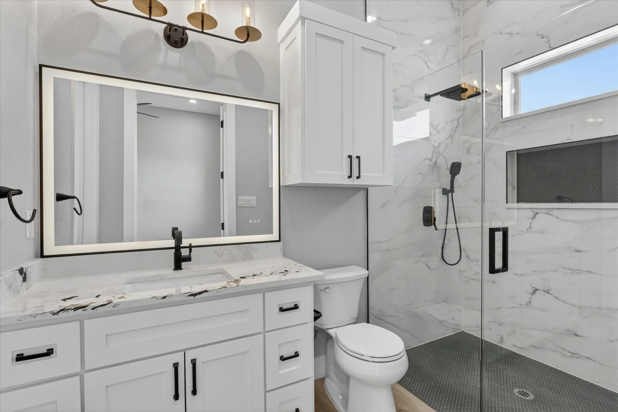 Modern bathroom featuring a glass-enclosed shower with contrasting dark tile flooring and a built-in niche