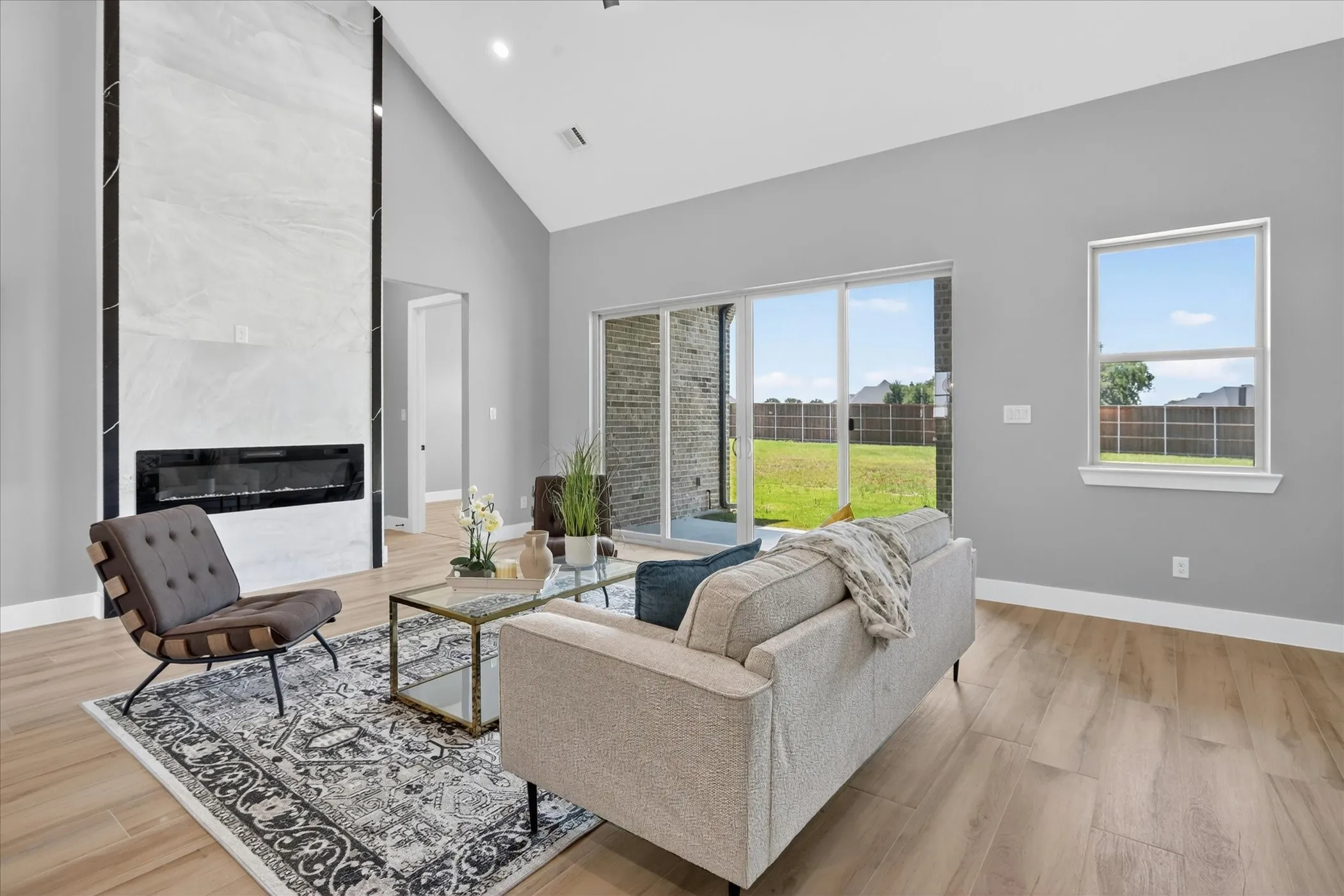 Spacious living area featuring a vaulted ceiling and light wood-finish flooring