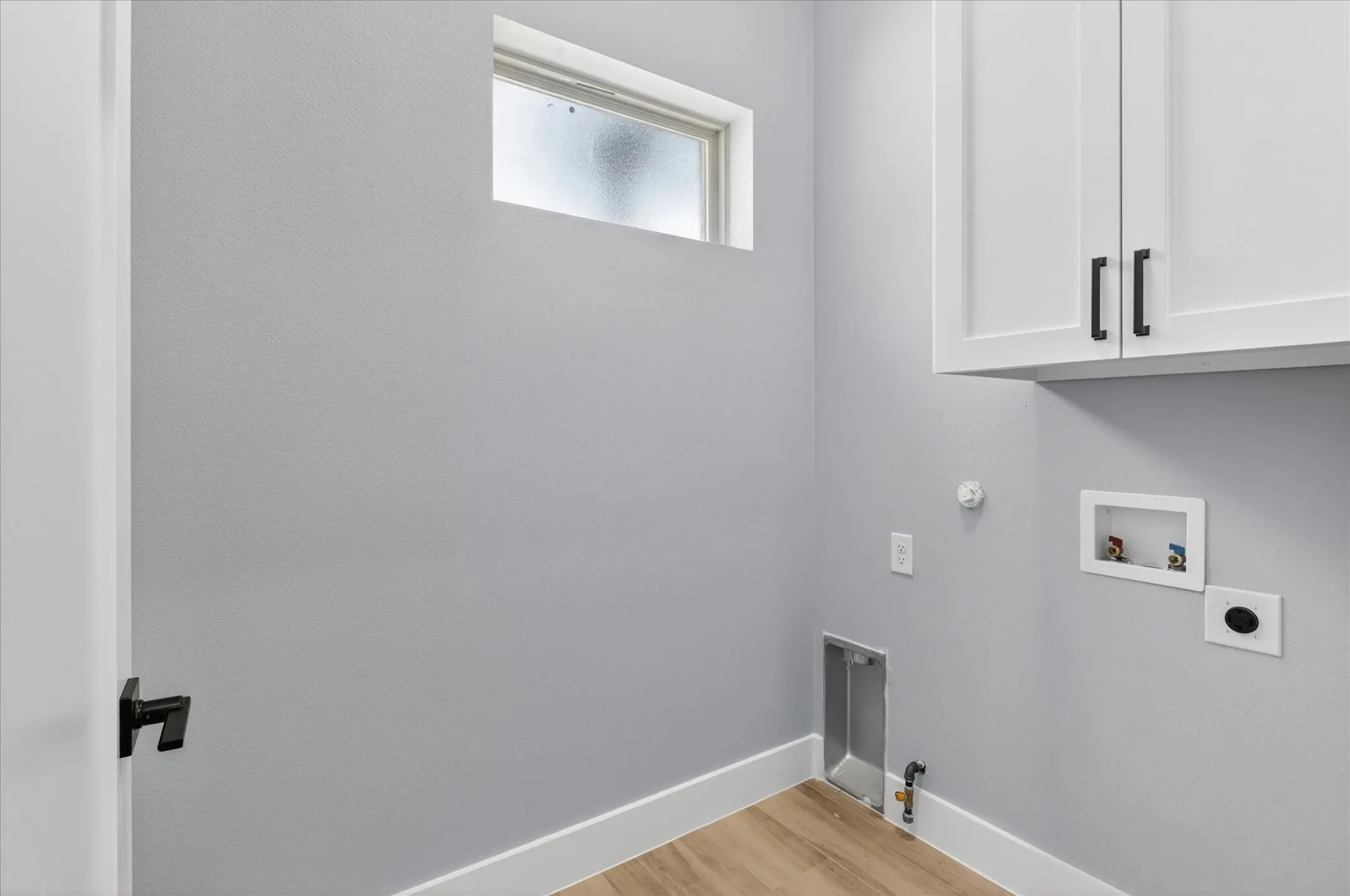 Functional utility space featuring light-colored walls and wood-finish flooring
