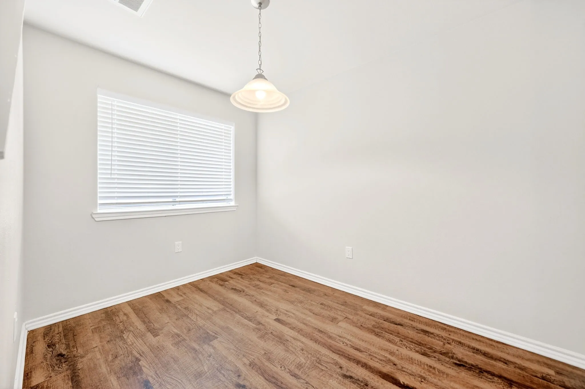 Room featuring wood-finish flooring, white baseboards, and neutral wall tones