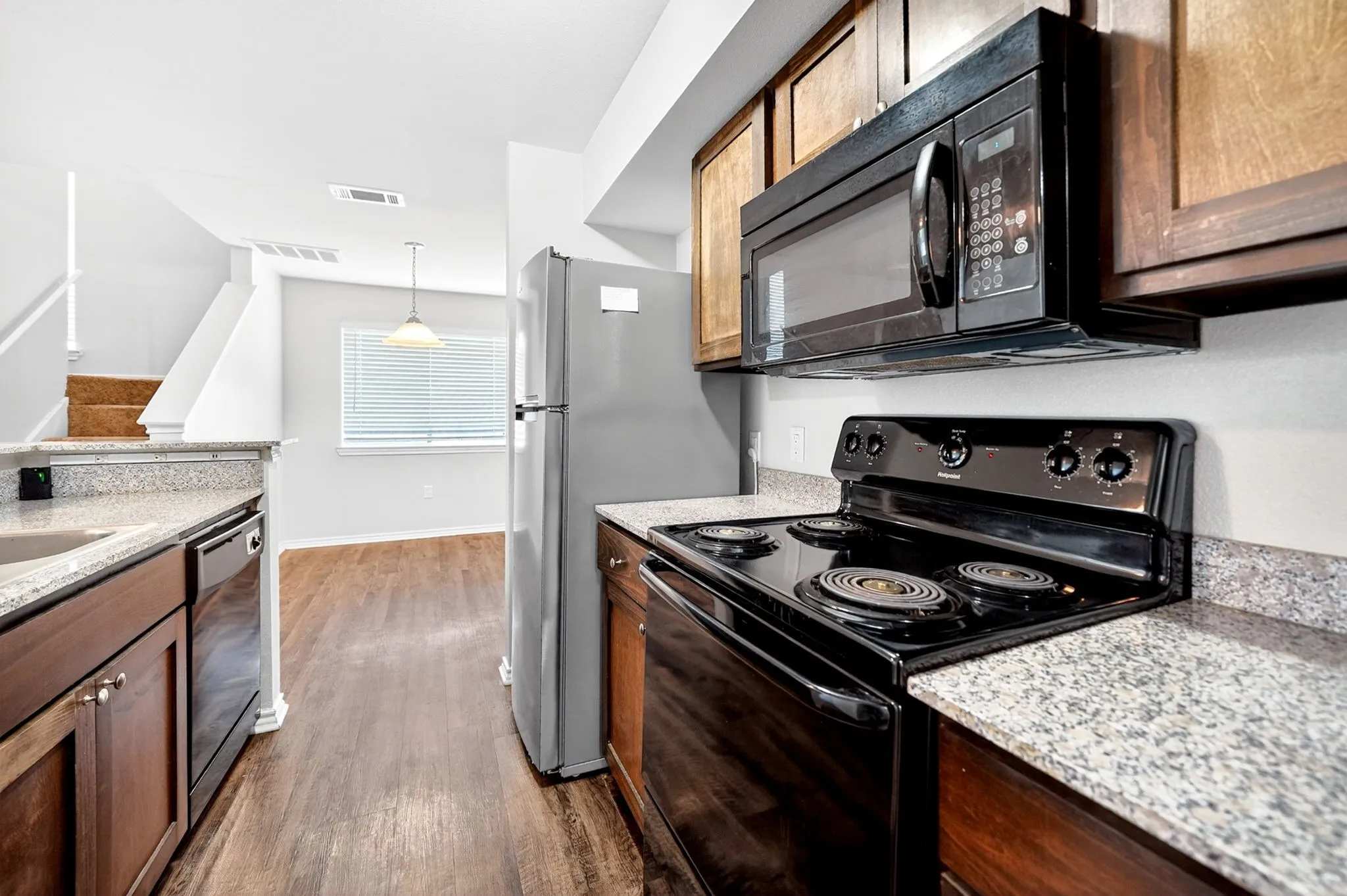 Kitchen featuring wood-finish flooring, granite-look countertops, and wood cabinetry