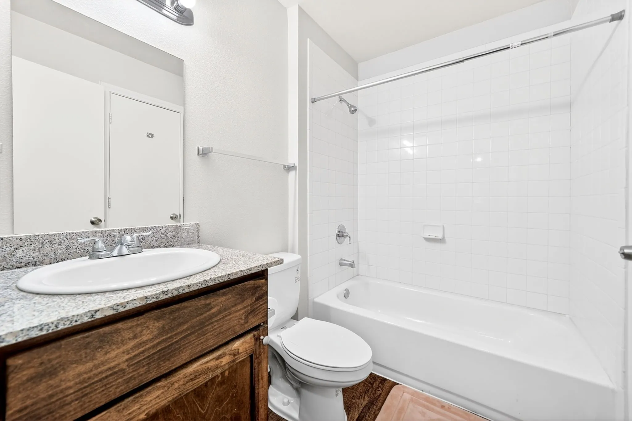Bathroom vanity with a granite countertop, undermount sink, and wood-finish cabinetry