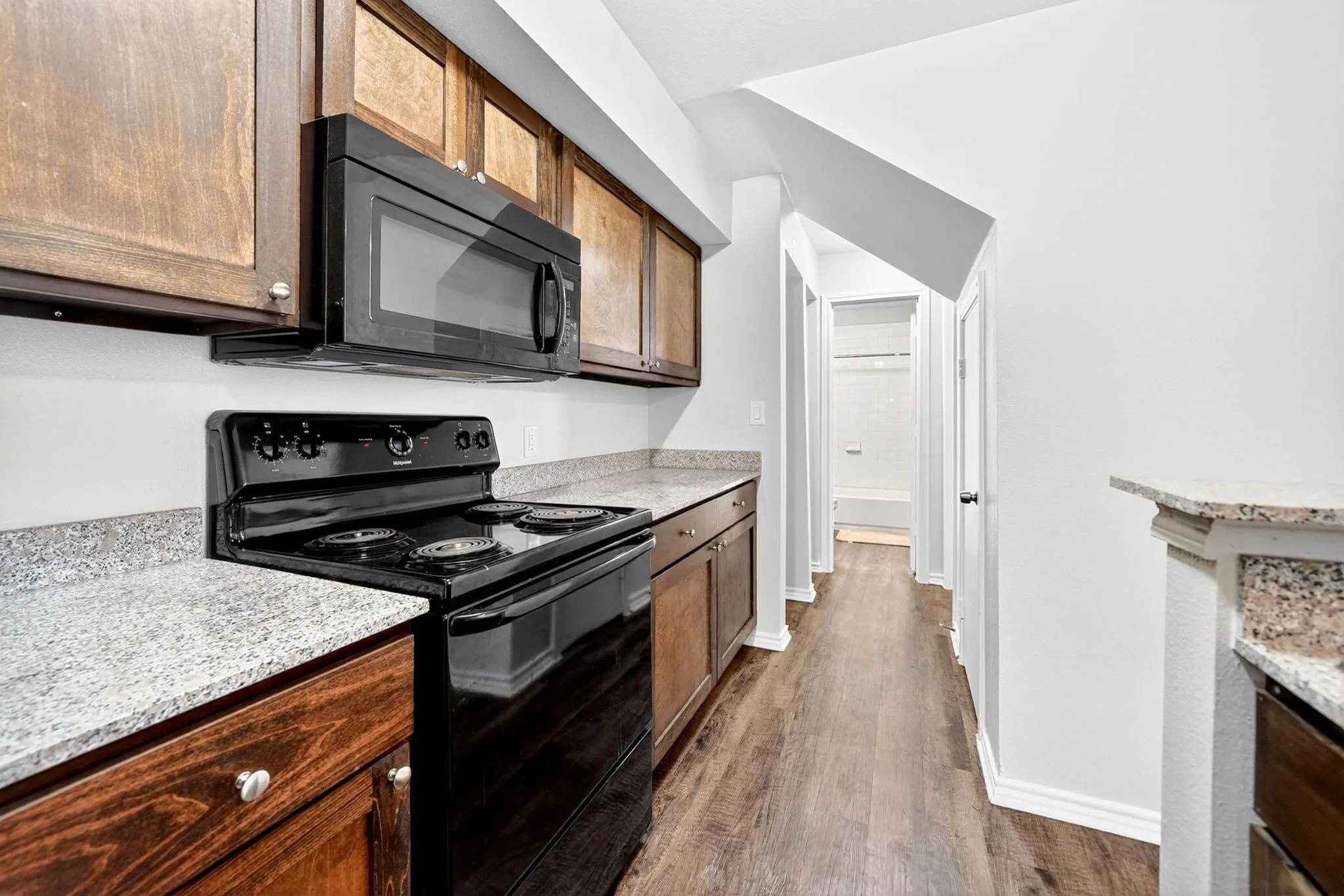 Kitchen featuring wood-finish cabinetry, speckled countertops, and a black appliance suite including a range and microwave