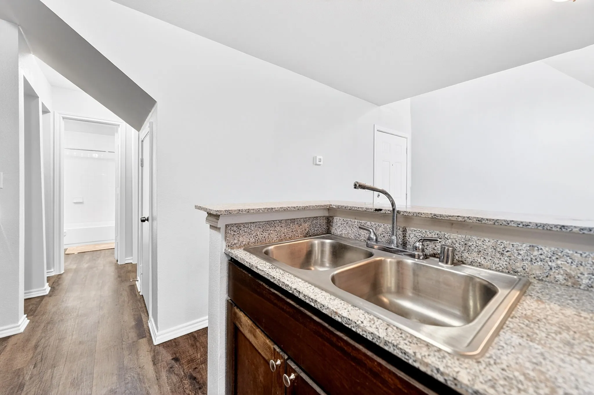 Double basin stainless steel sink with a high-arc faucet, set within a speckled countertop