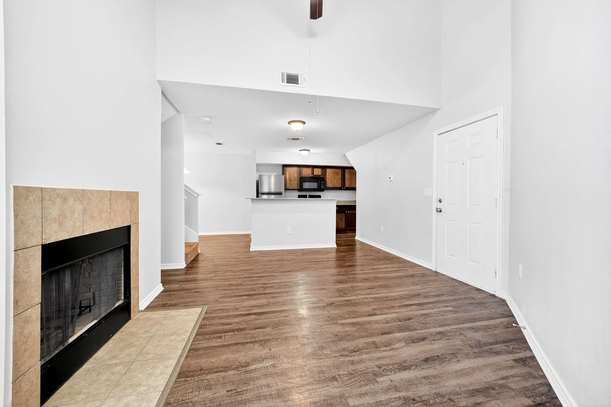 Living area featuring wood-finish flooring, a tiled fireplace, and vaulted ceilings