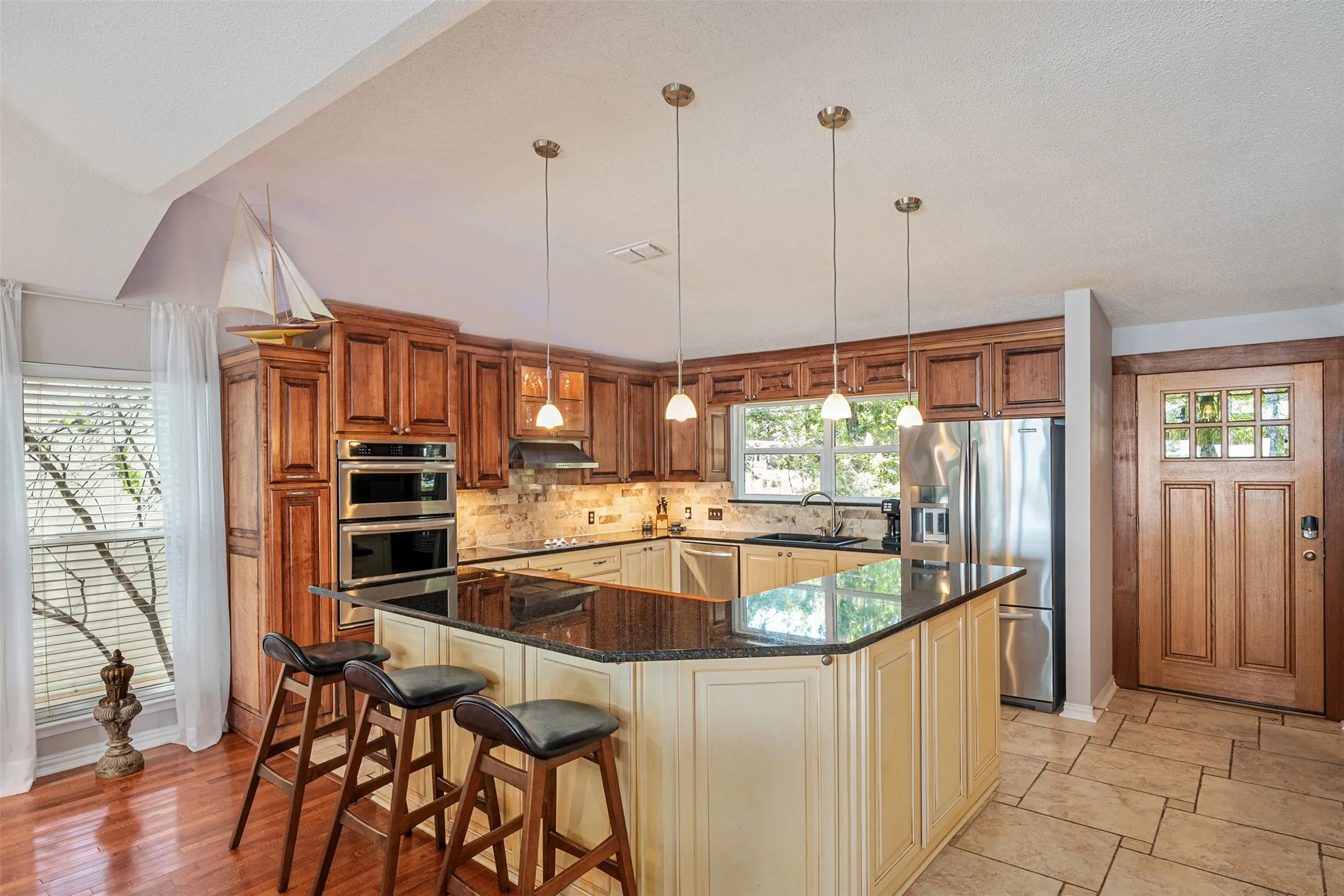 Kitchen featuring a multi-level island with dark countertops, wood cabinetry, and stainless steel appliances