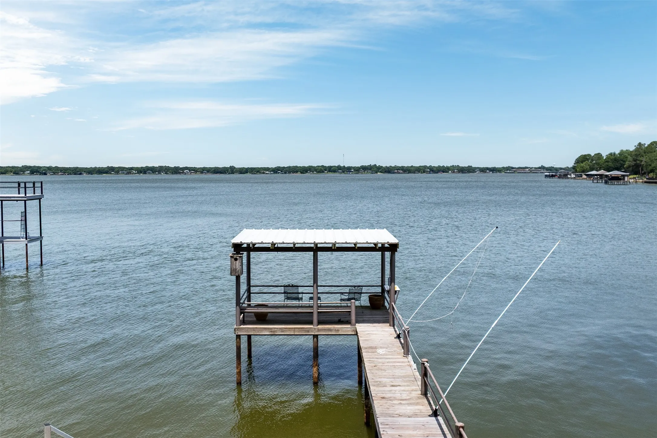 Private covered boat dock featuring a metal roof, wood decking, and lake access