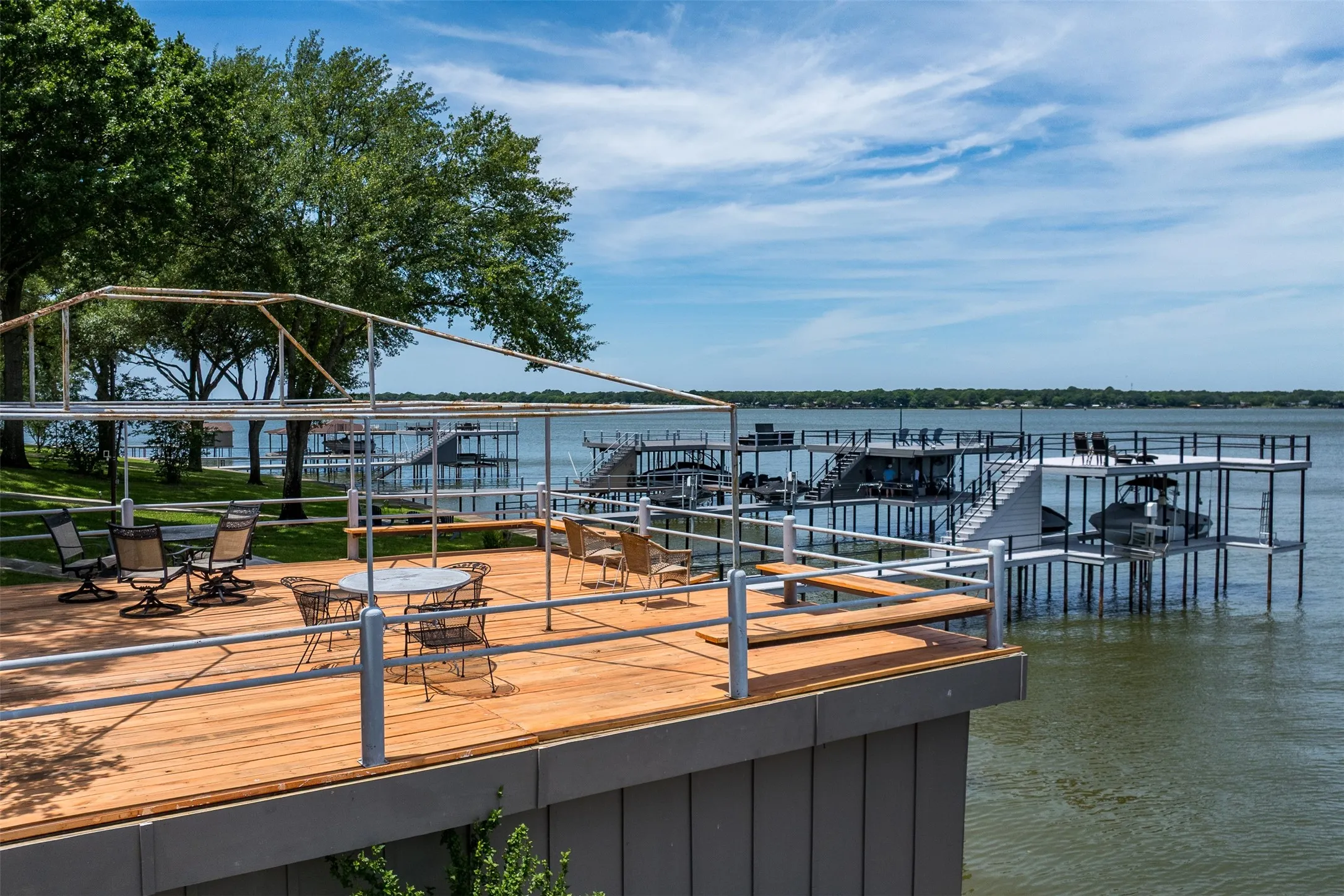 Expansive wood-finish deck with metal railings and a structural framework for a canopy