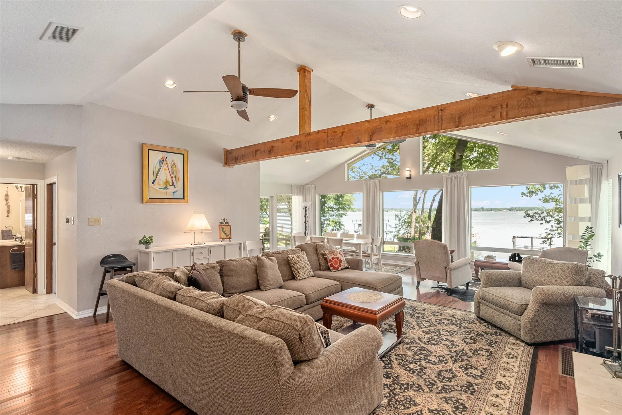 Spacious living area featuring vaulted ceilings with exposed wood beams, recessed lighting, and a ceiling fan