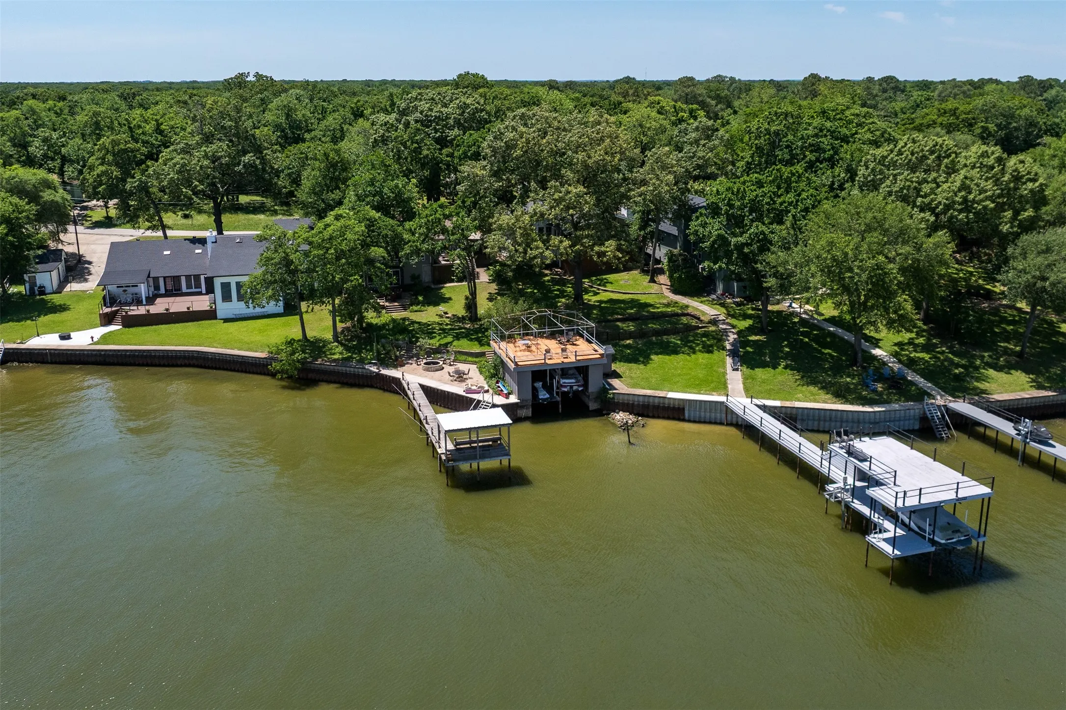 Waterfront property featuring multiple boat docks, a large deck, and extensive tree coverage