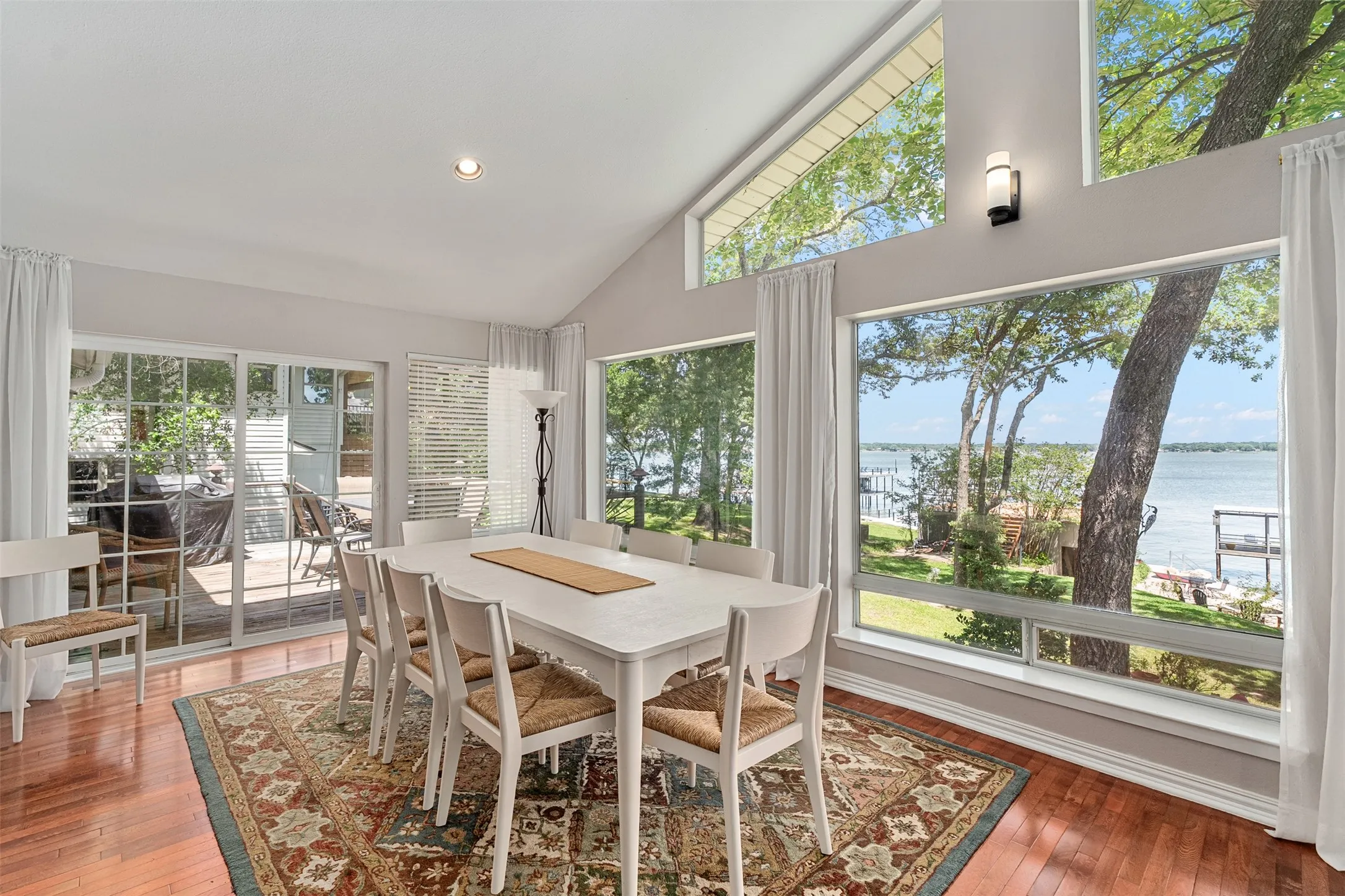 Dining area featuring panoramic windows with water scenery, wood-finish flooring, a vaulted ceiling, and recessed lighting