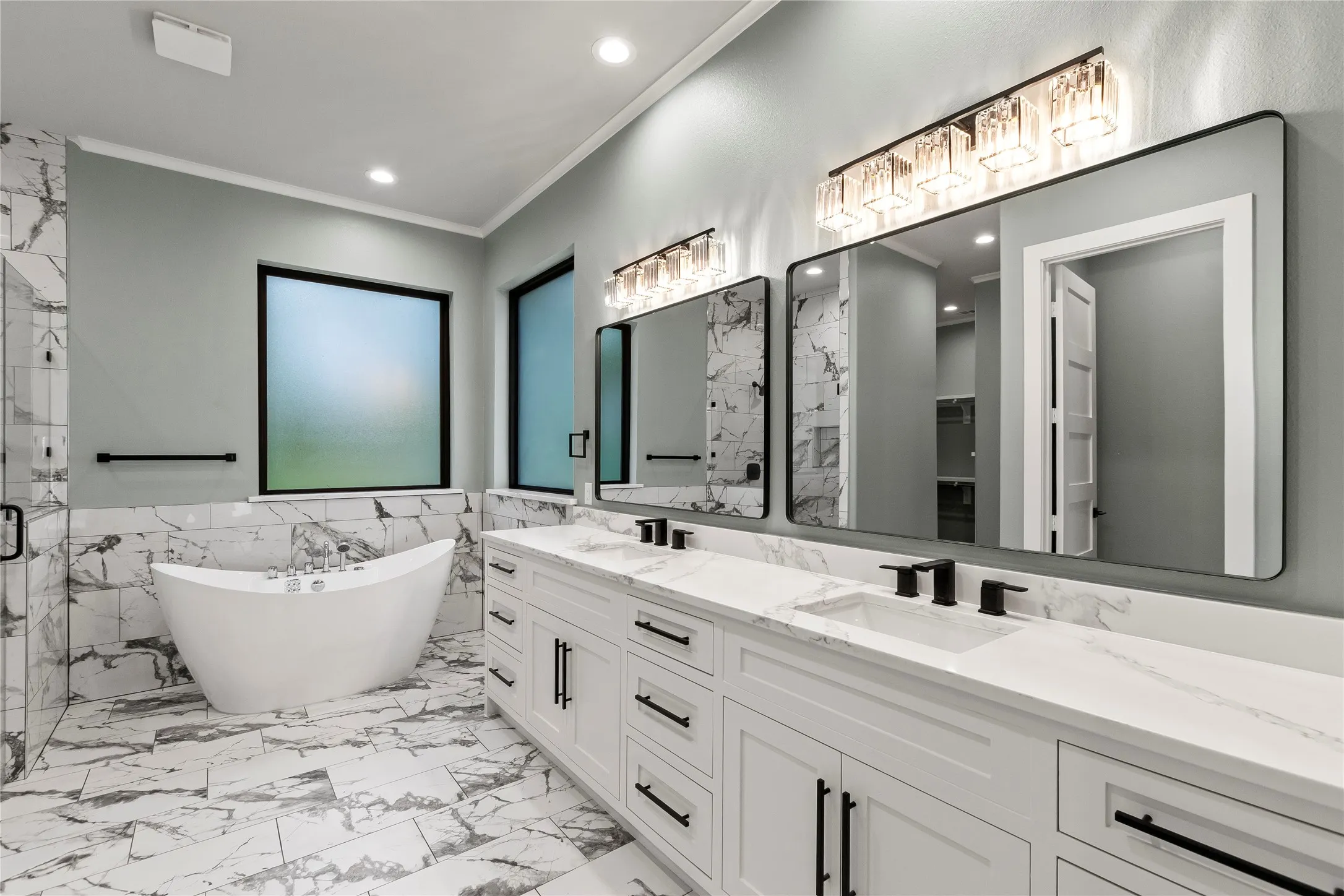 Luxurious primary bath with freestanding soaking tub, oversized walk-in shower, dual vanities, and direct access to the custom closet.