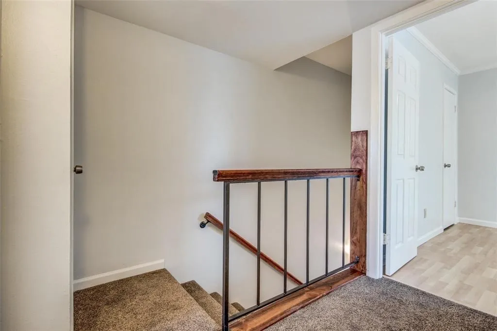 Carpeted staircase with dark wood-finish handrail