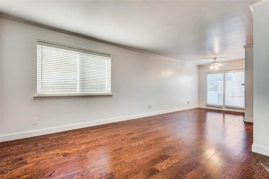 Spacious living room featuring wood-finish flooring, white baseboards, and crown molding