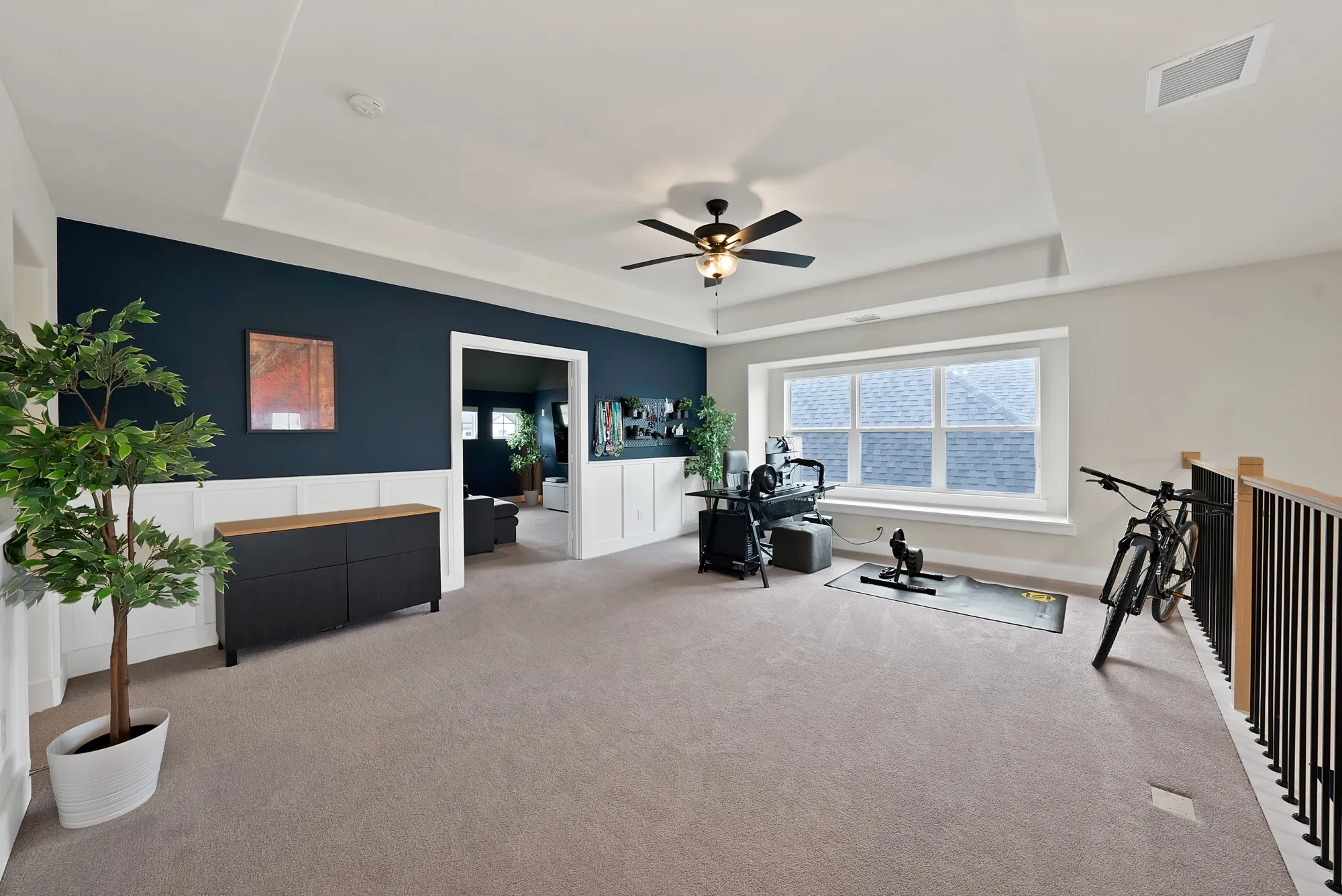 Good size game room with a window seat, accent wall and a tray ceiling.