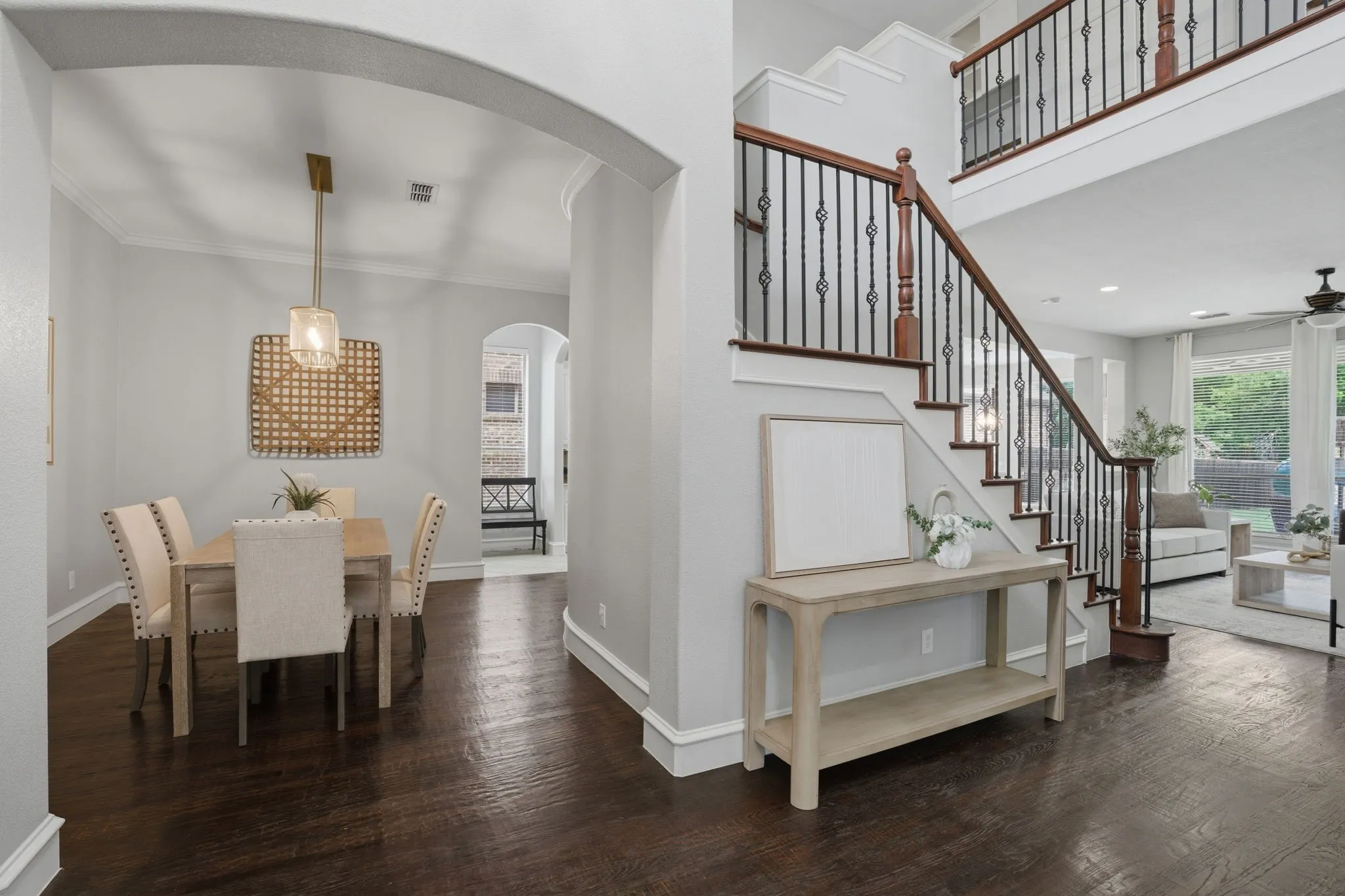 Formal dining space with a pendant light fixture, dark wood-finish flooring, an arched entryway, and crown molding