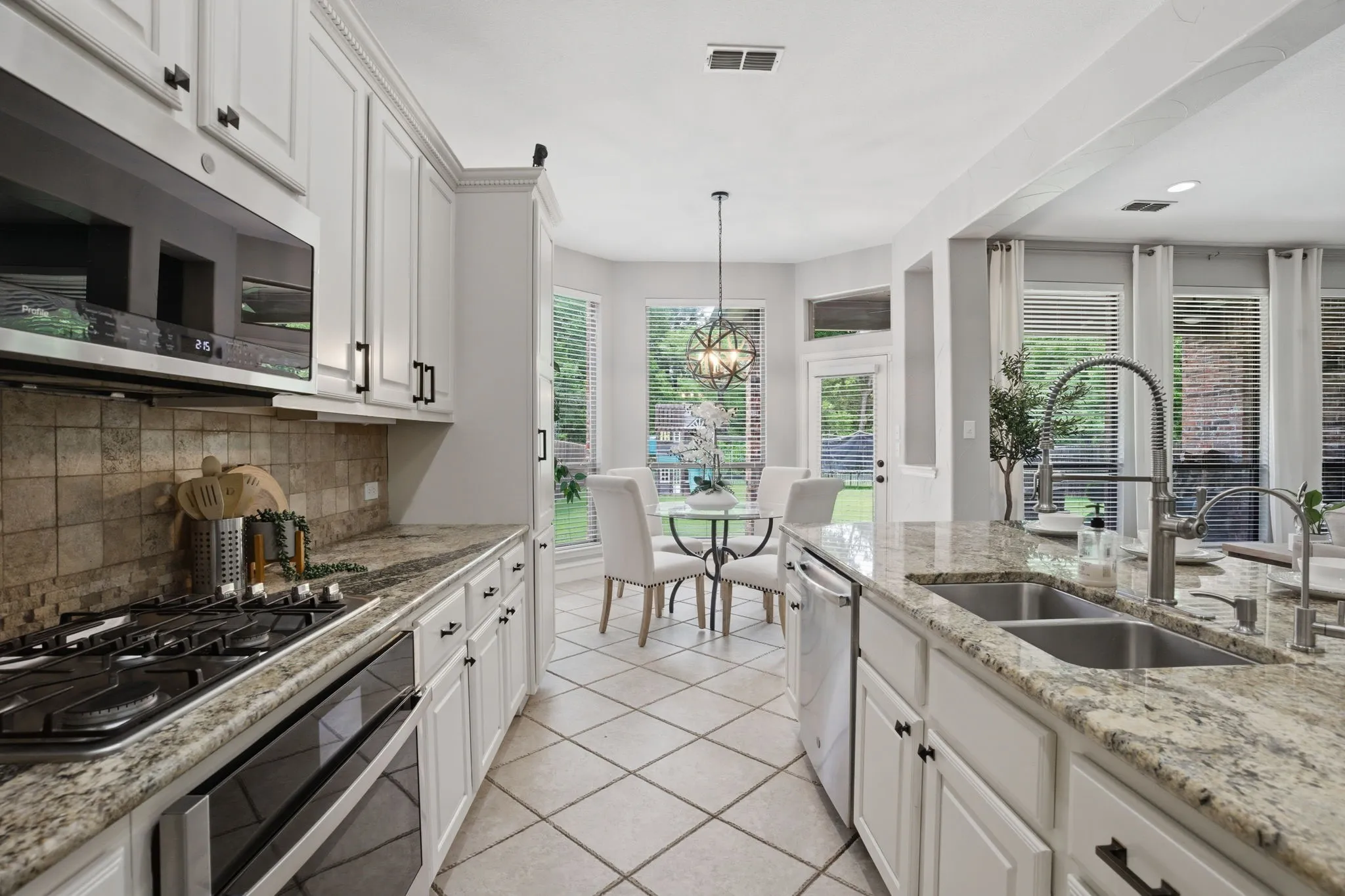 Gourmet kitchen featuring white cabinetry, granite countertops, tile backsplash, and a stainless steel gas range
