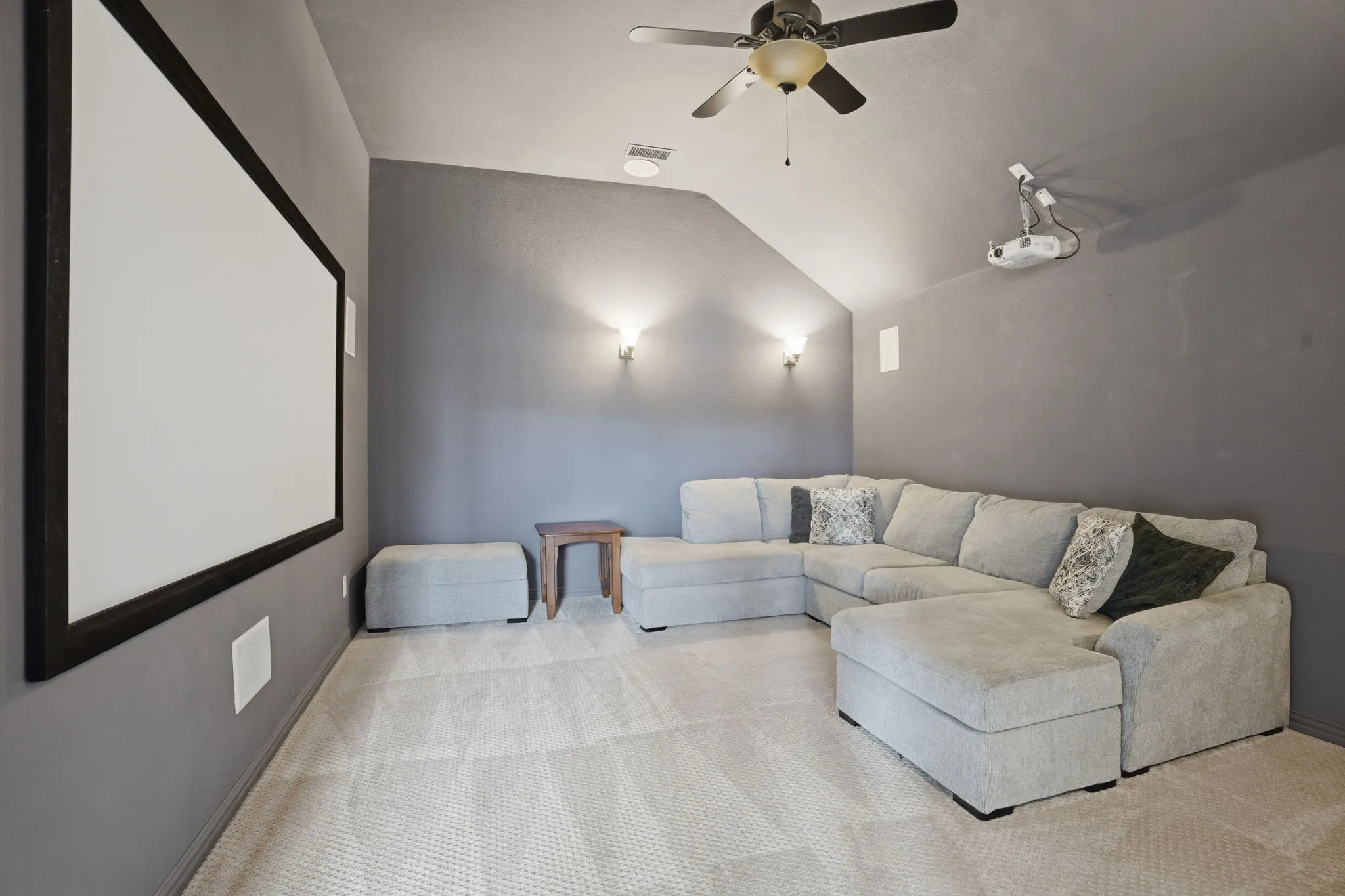 Dedicated media room featuring a large projector screen, mounted projector, and a ceiling fan