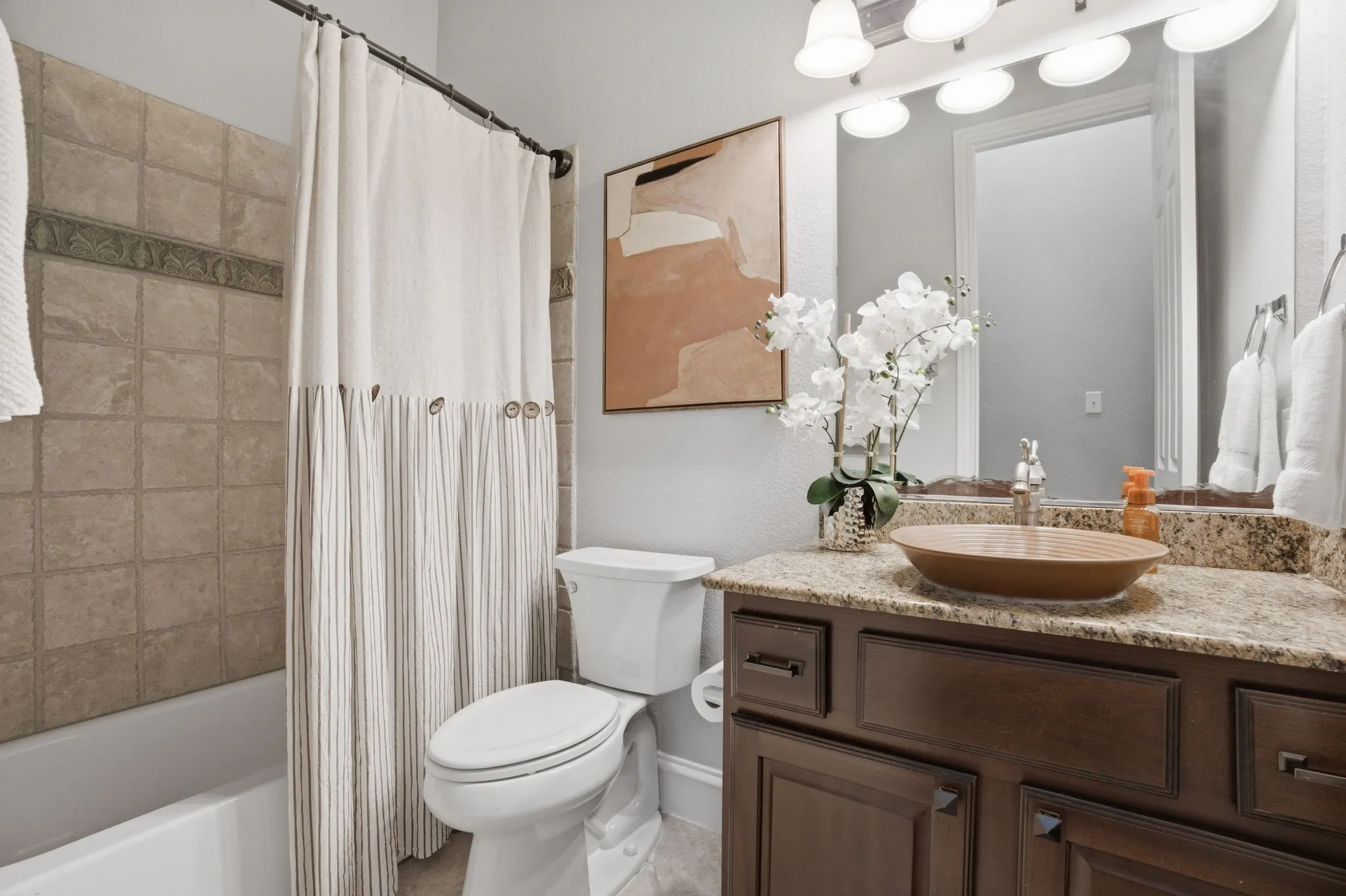 1st level secondary bathroom vanity with a vessel sink, speckled countertop, and dark wood cabinetry