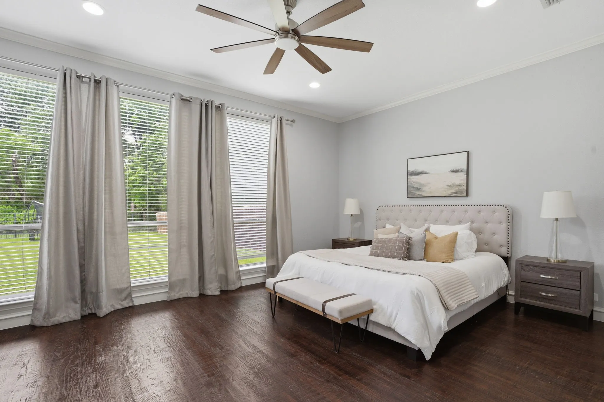 Room featuring rich wood-finish flooring and three large windows with horizontal blinds