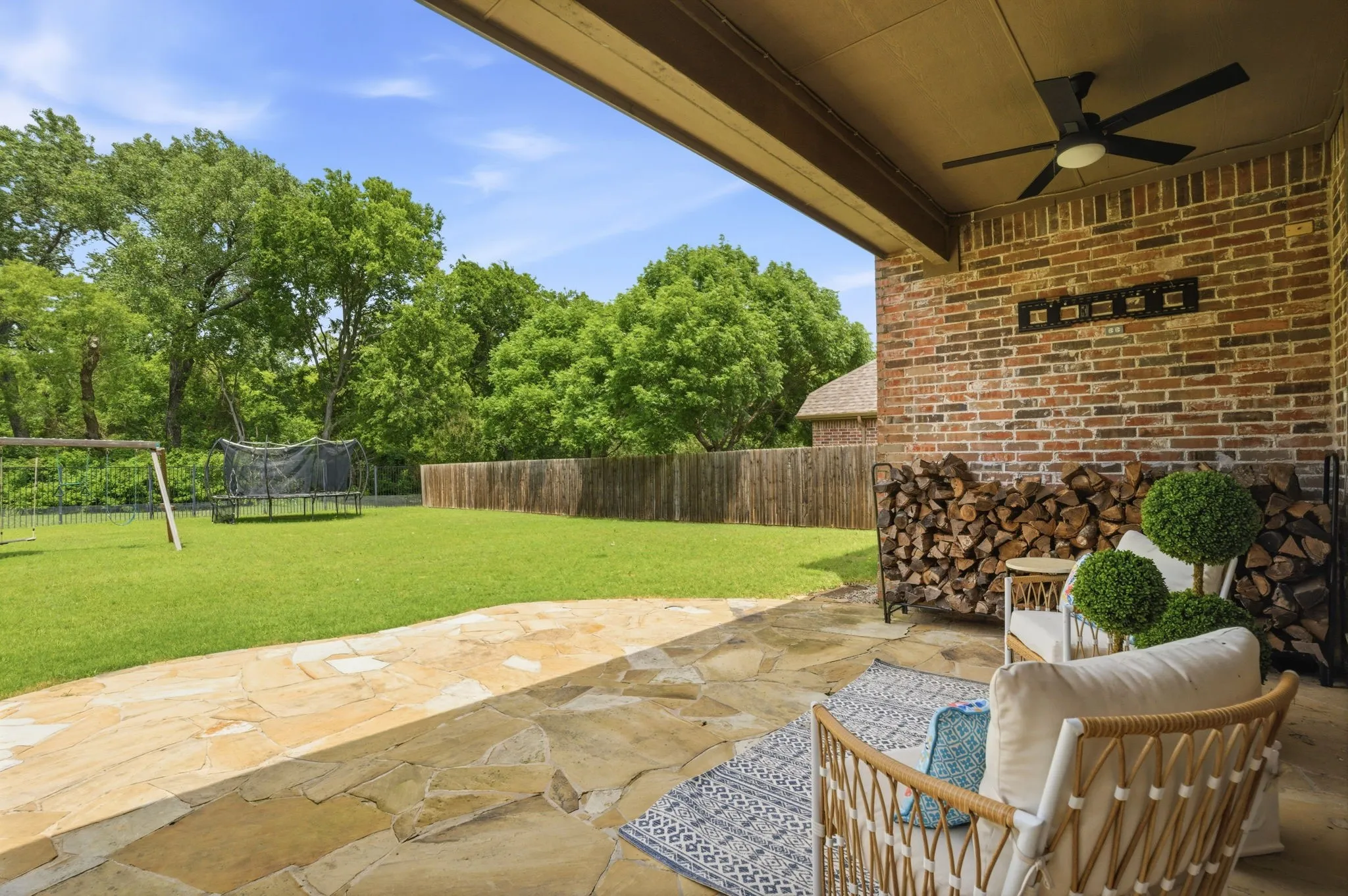 Covered patio with flagstone flooring, brick exterior, and a ceiling fan