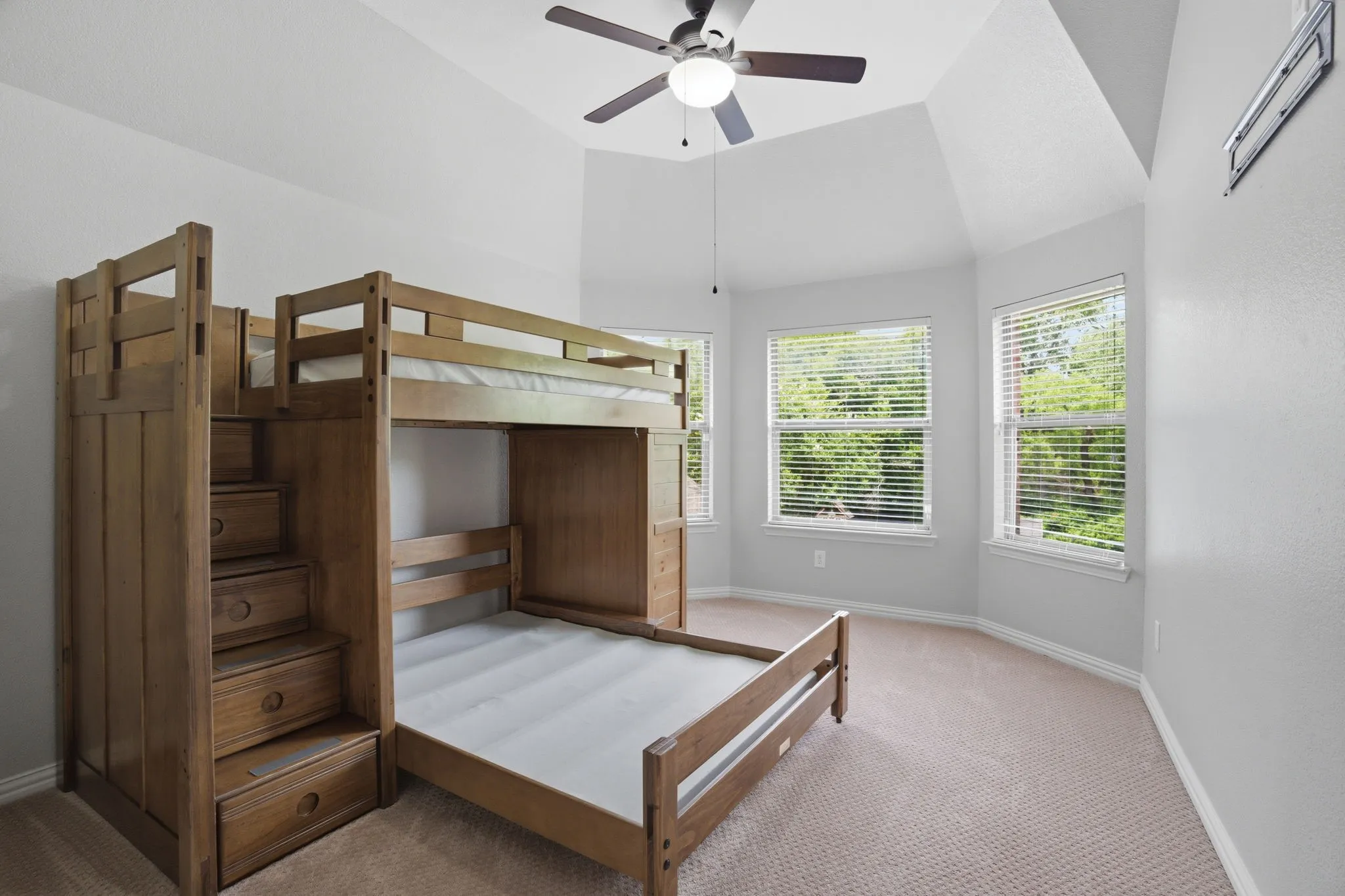 Vaulted ceiling bedroom with a ceiling fan, light gray wall paint, and carpet flooring