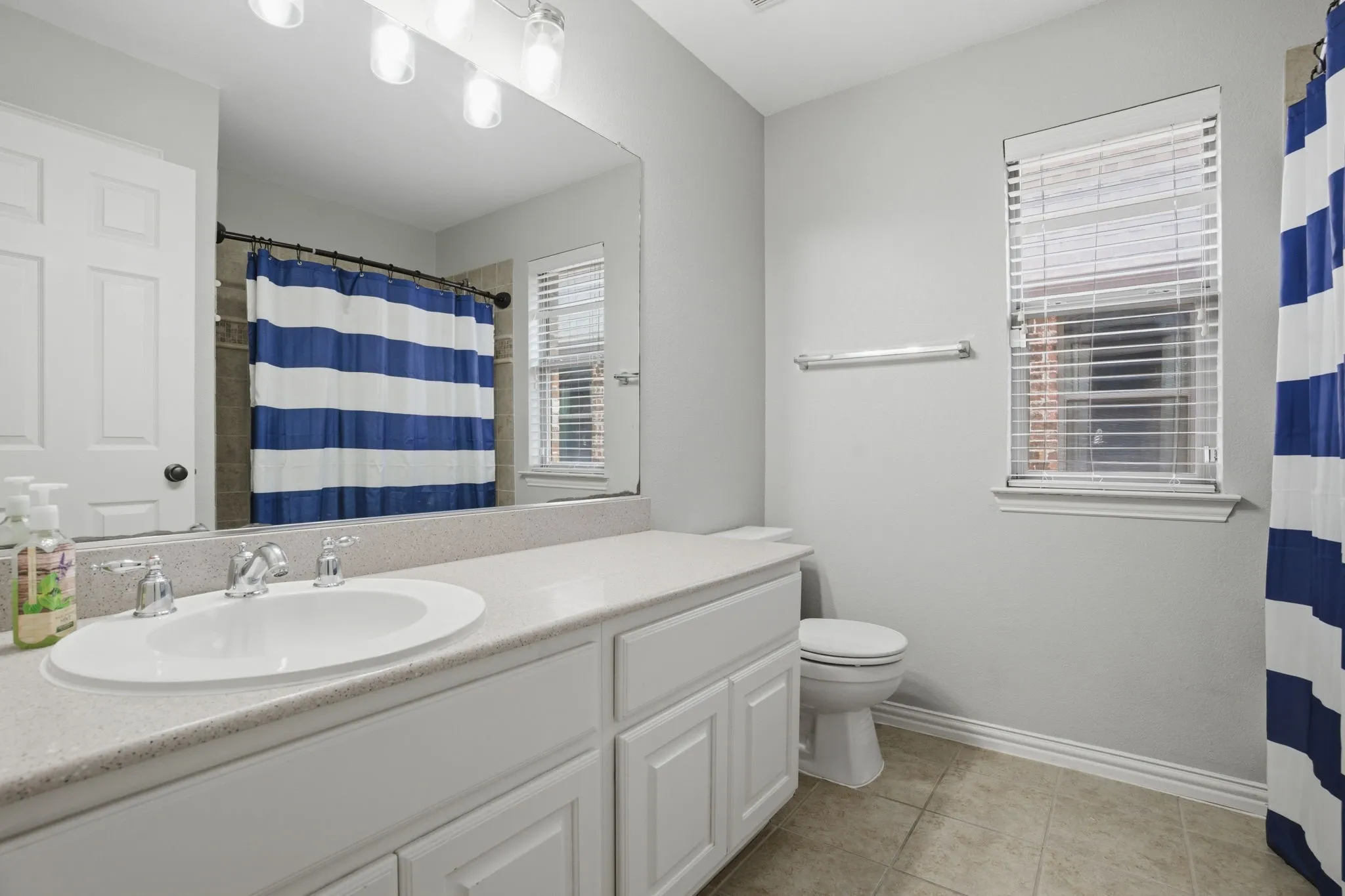 Bathroom featuring a white vanity with an integrated sink, polished chrome faucet, and a large wall mirror
