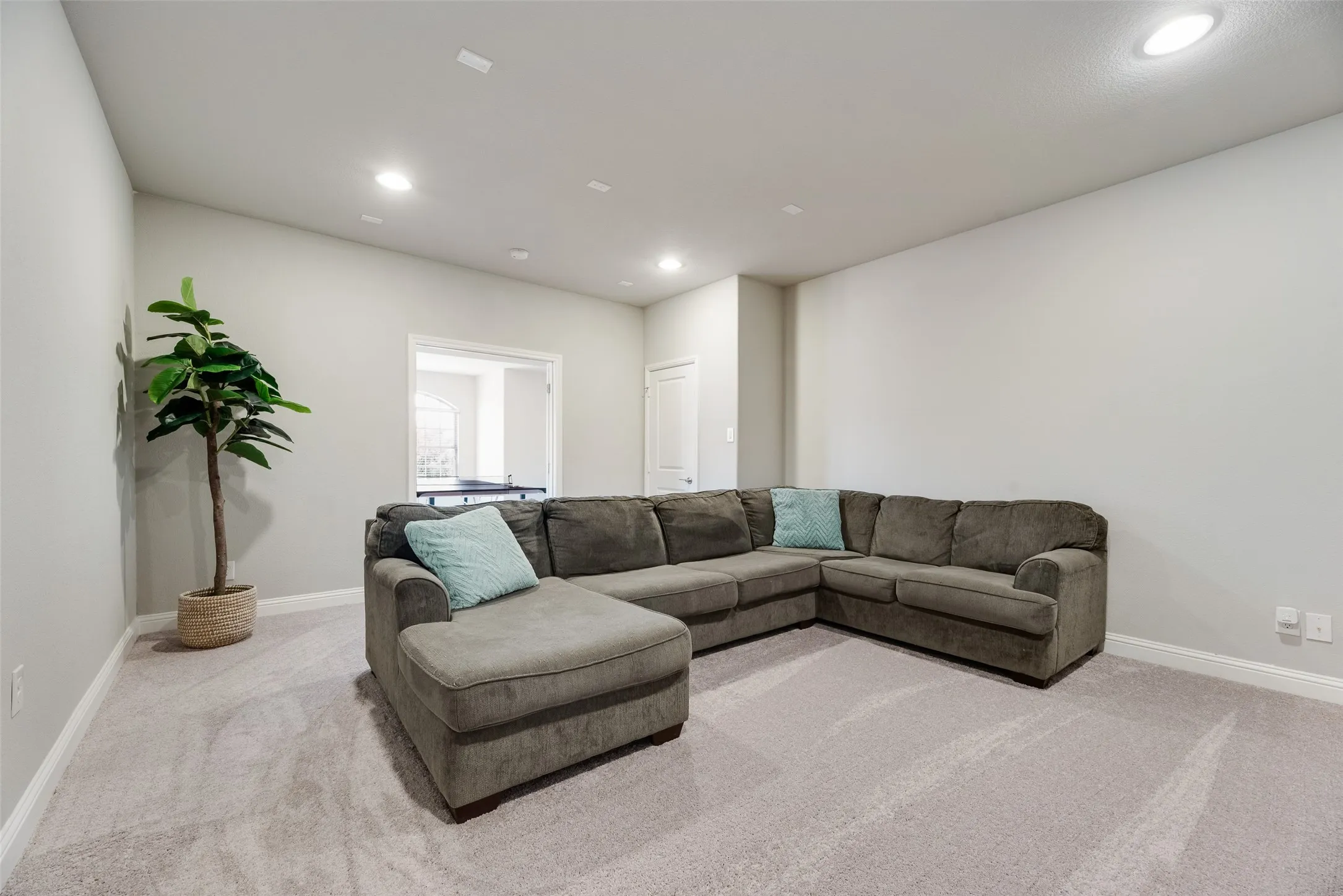 Spacious media room featuring light gray wall paint, recessed lighting, and light-toned carpeting