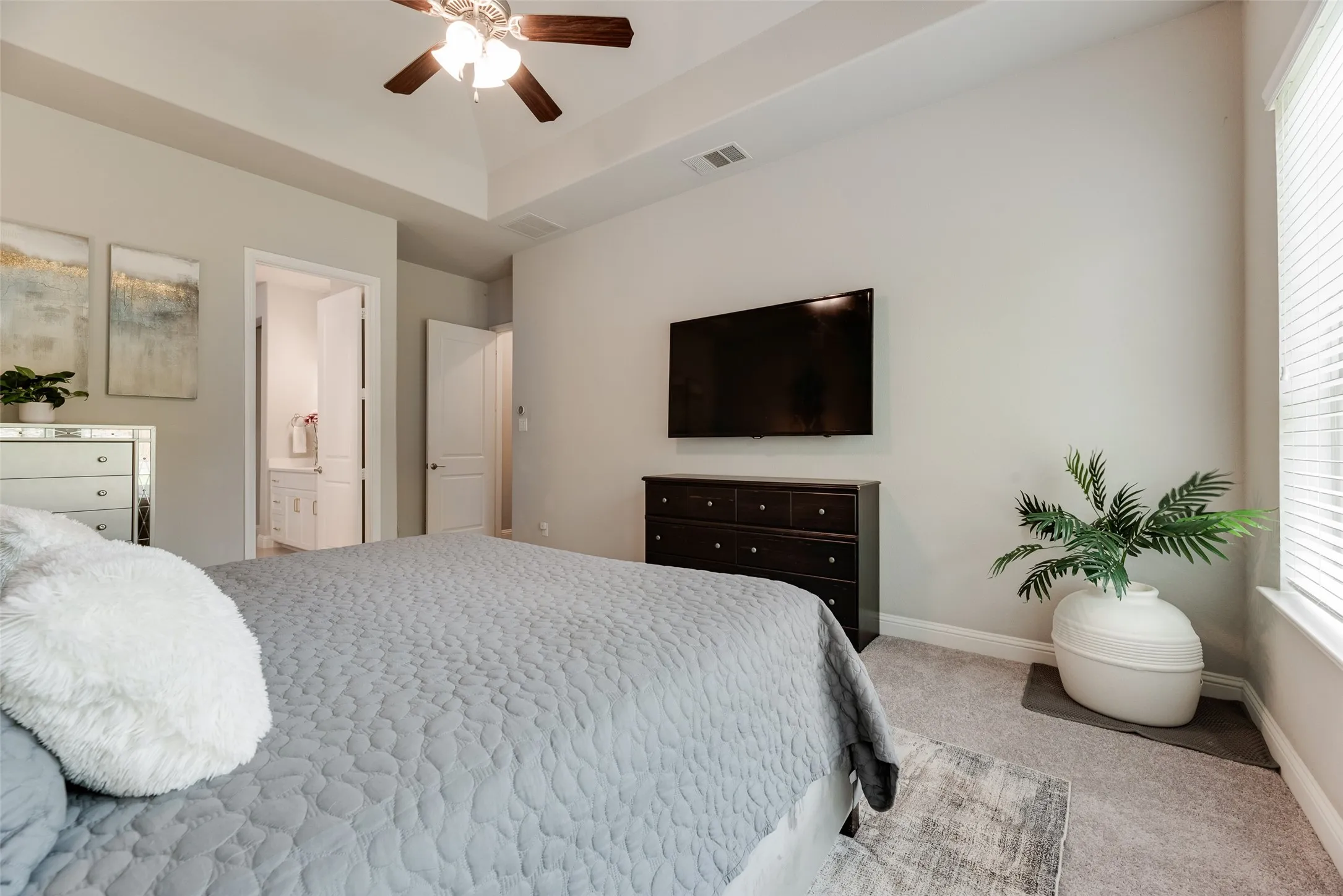 Bedroom featuring a tray ceiling with a ceiling fan, light-colored walls, and carpet flooring