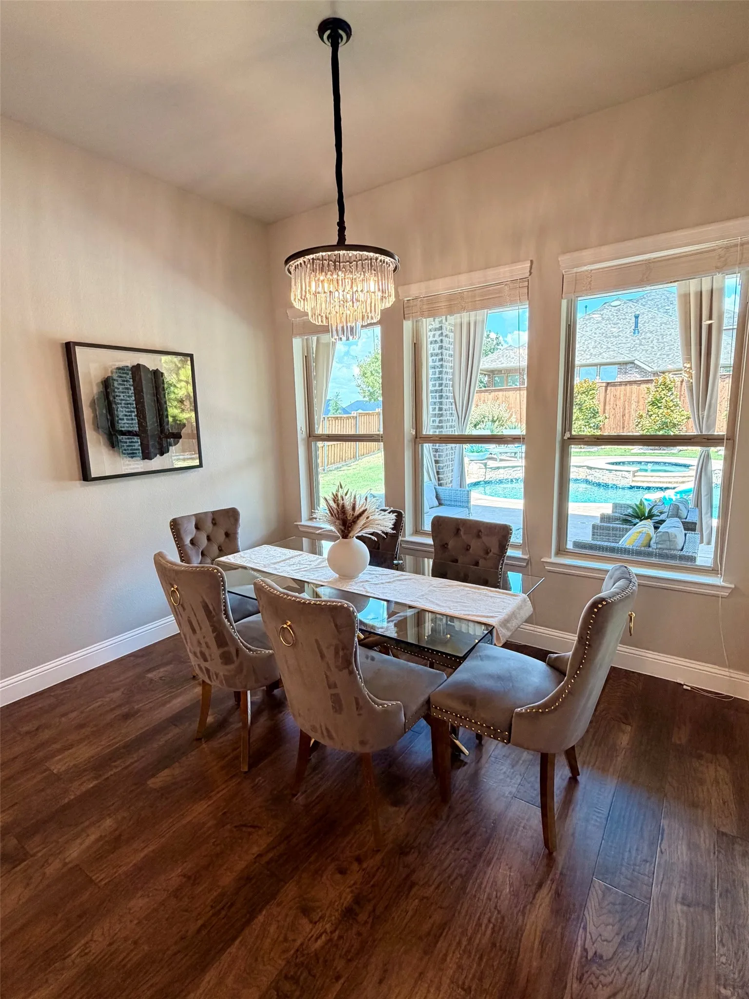 Expansive wood-finish flooring, three large windows, and a built-in chandelier with tiered crystal accents