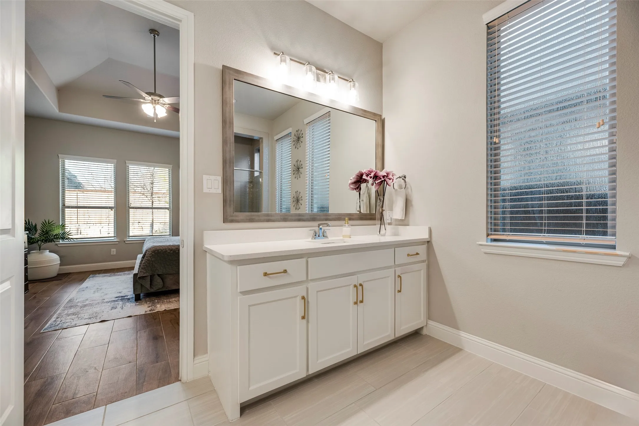 Vanity with white cabinetry, gold-toned hardware, and a light-colored countertop