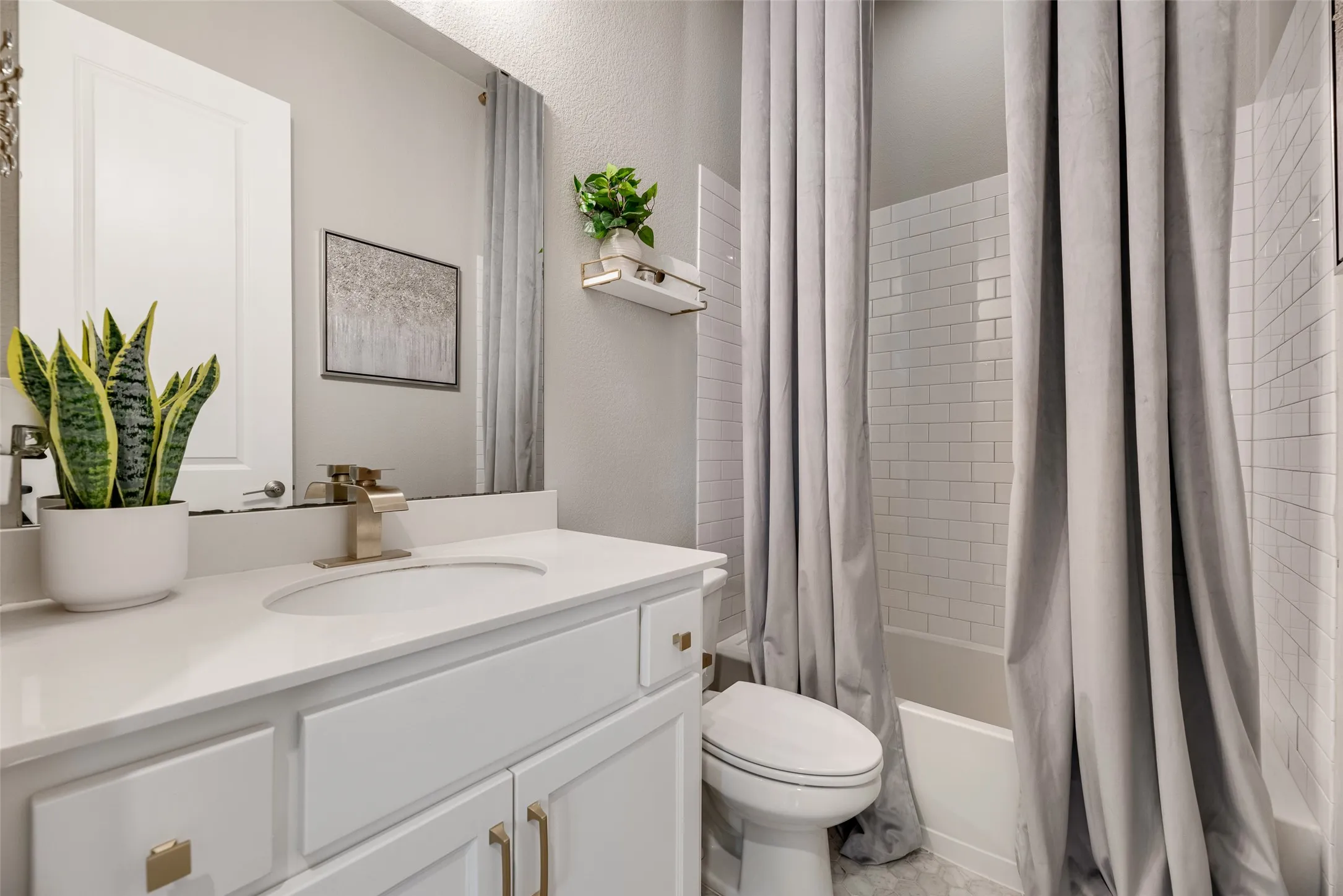 Bathroom featuring a white vanity with gold-finish hardware, a white countertop, and a rectangular undermount sink with a gold-finish faucet