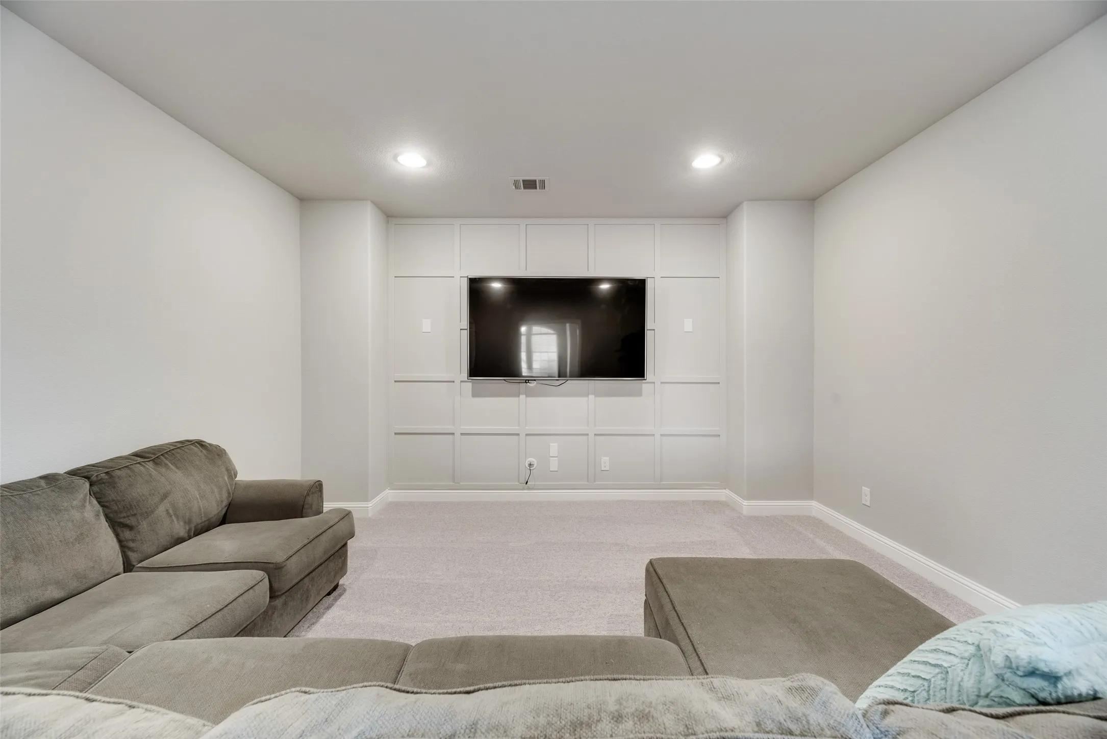 Recessed wall paneling with a mounted display, light gray walls, and light gray carpeting