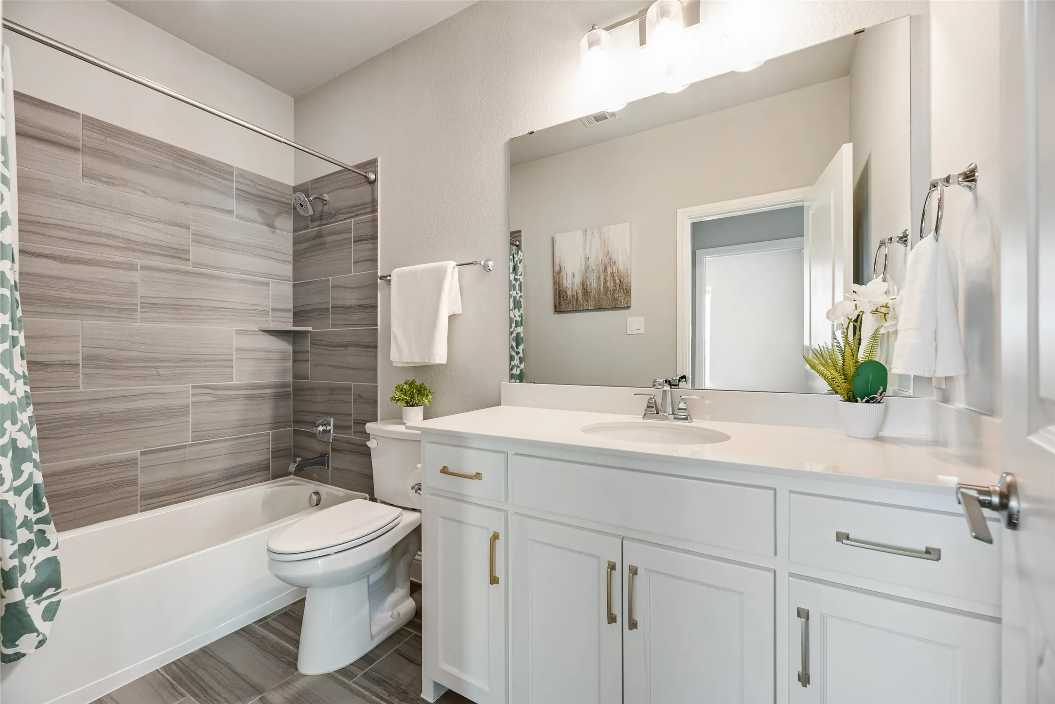 Bathroom featuring a white vanity with a light-toned countertop, a large mirror, and an overhead light fixture