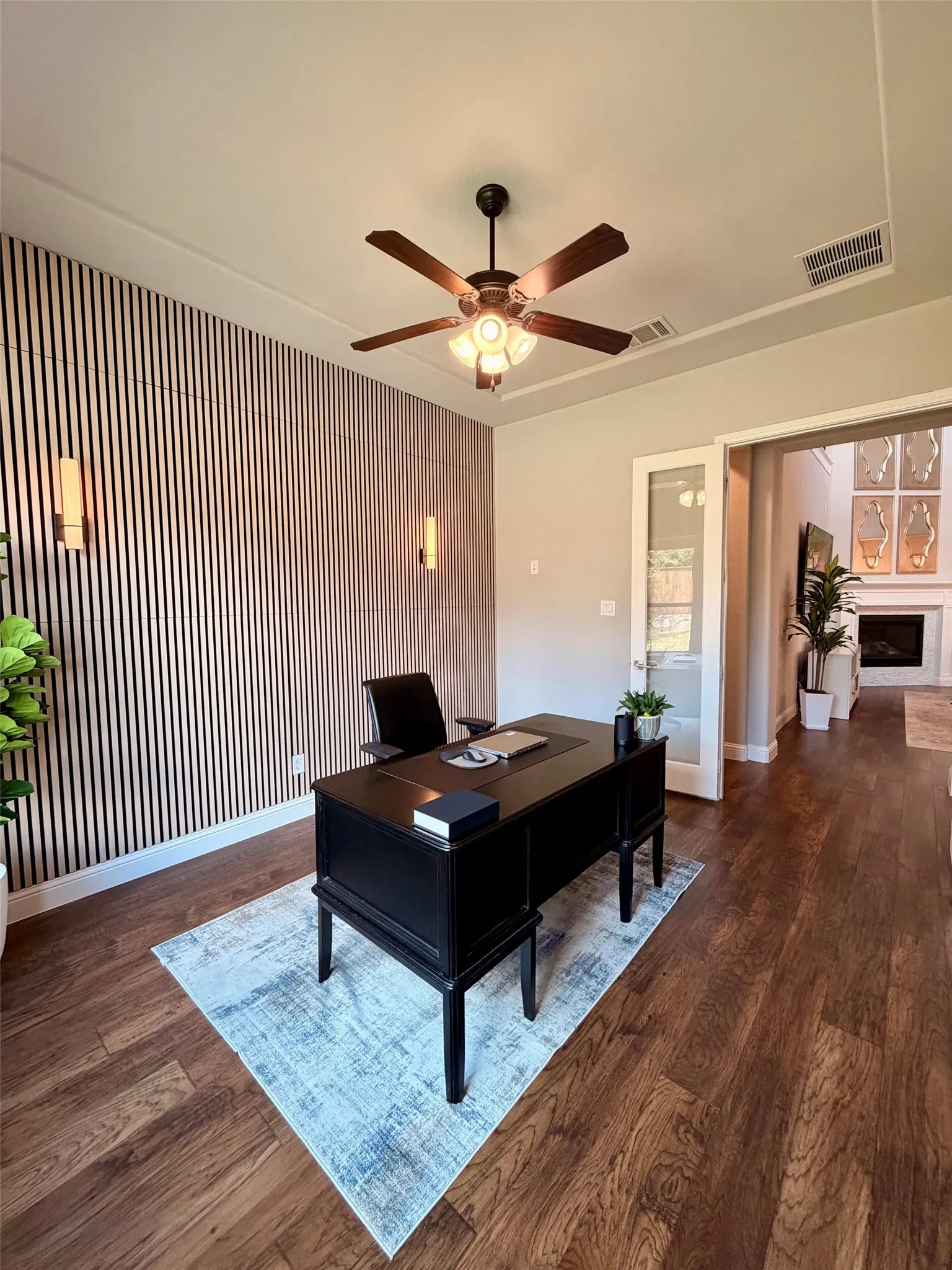 Wood-finish flooring, accent wall with vertical paneling, recessed lighting, and a ceiling fan with integrated lighting
