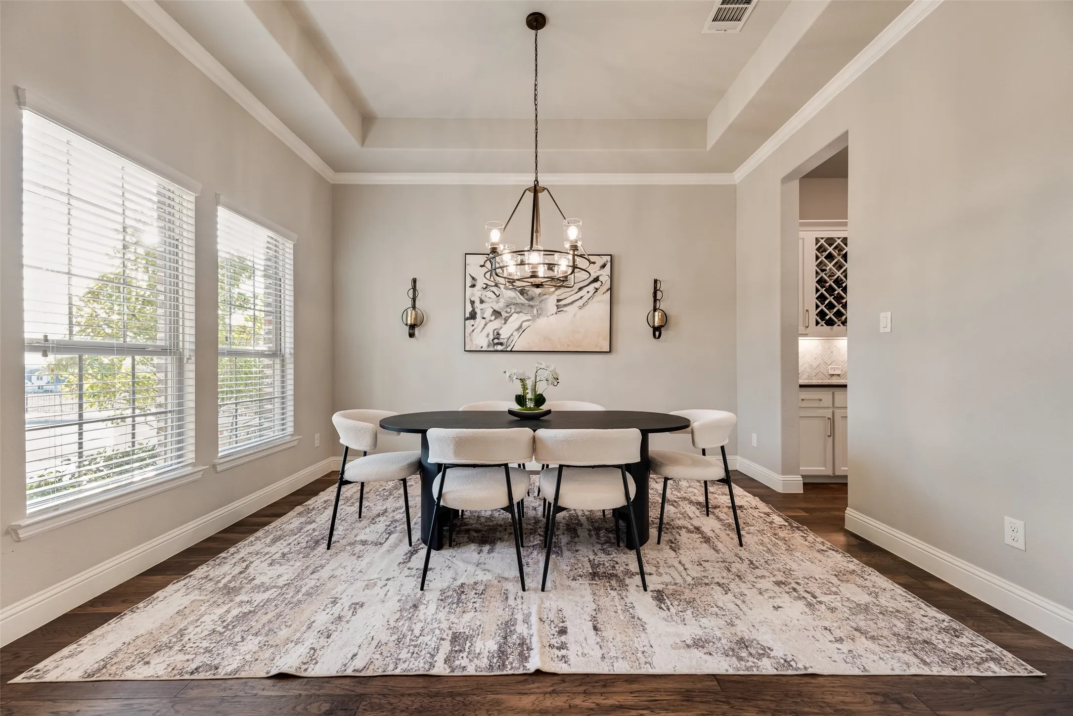 Spacious dining area featuring dark wood-finish flooring, a tray ceiling, and crown molding