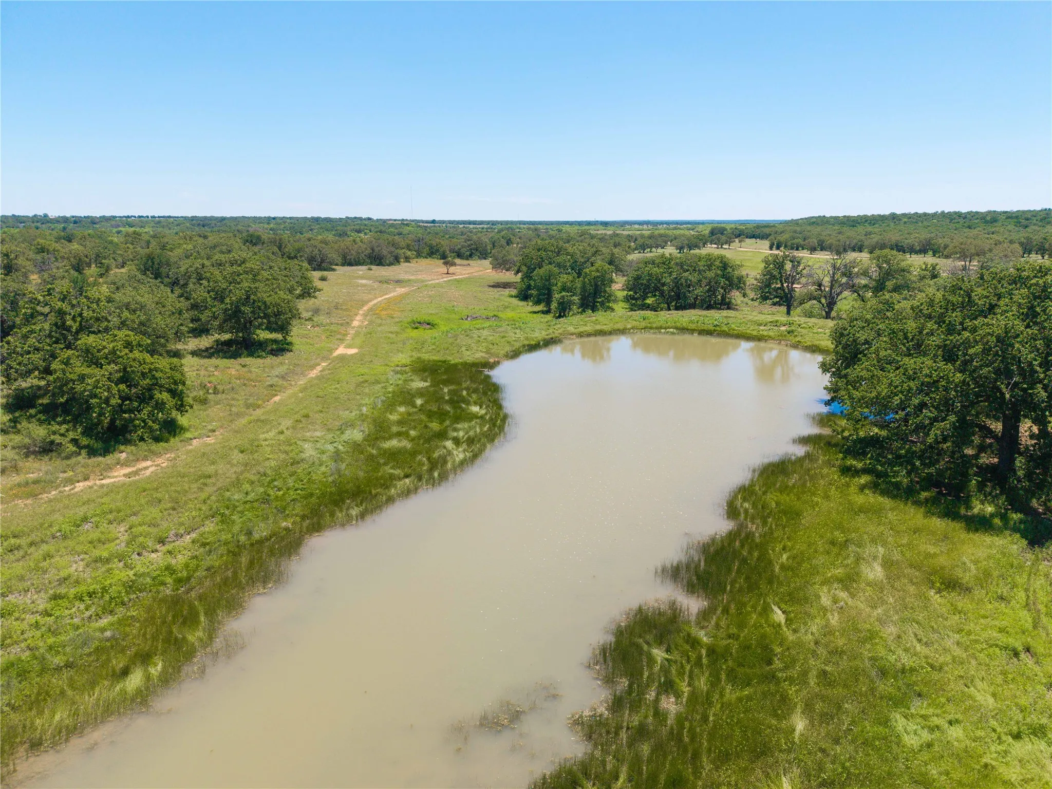 Expansive natural landscape featuring a large pond and mature trees