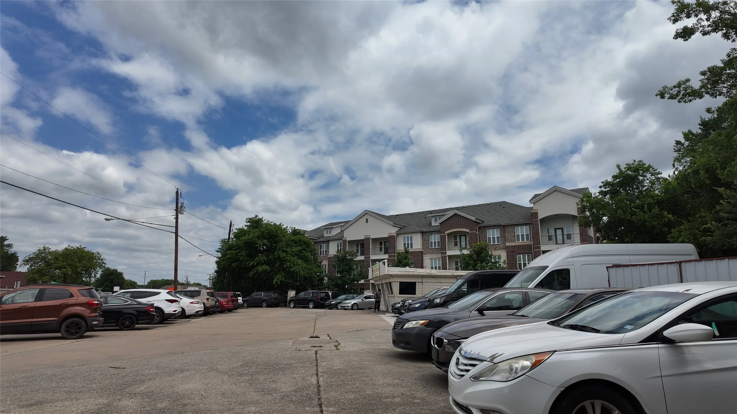 Paved parking lot with ample space, featuring a backdrop of multi-story buildings with brick and siding exteriors