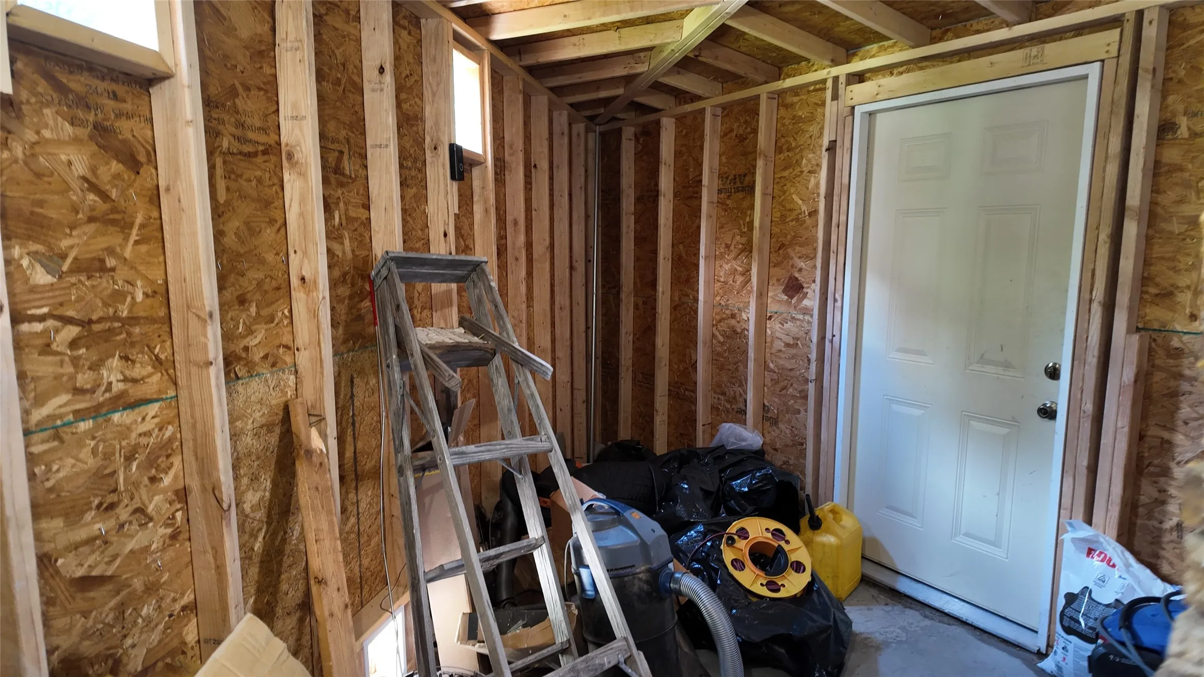 Interior framing and unfinished walls with a white panel door