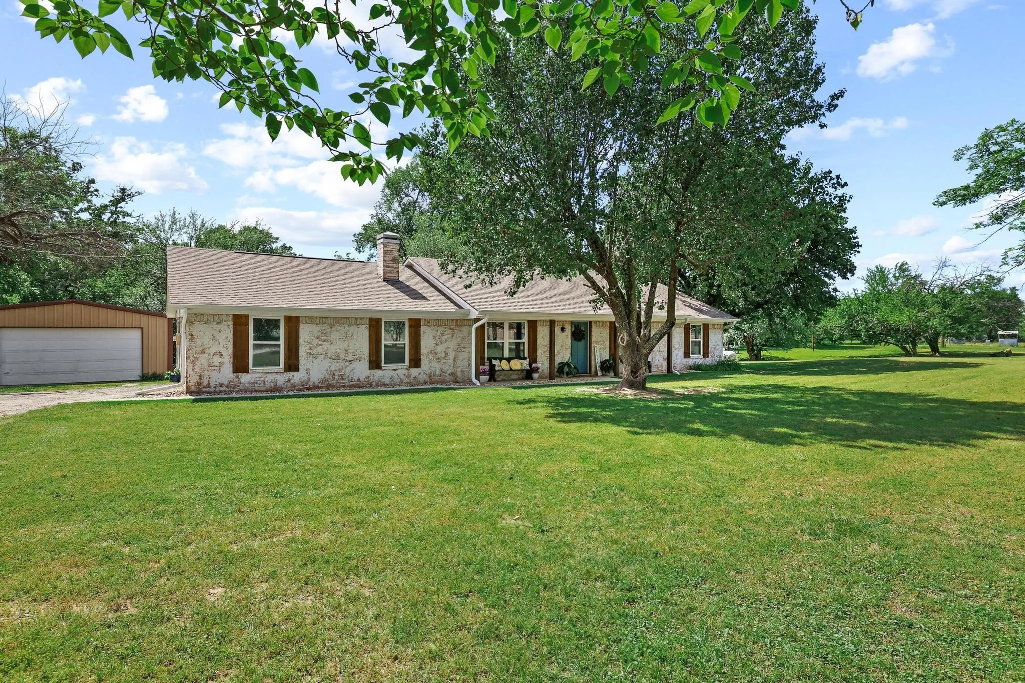 Ranch-style residence featuring a textured facade, a covered front porch, and a light-toned shingle roof